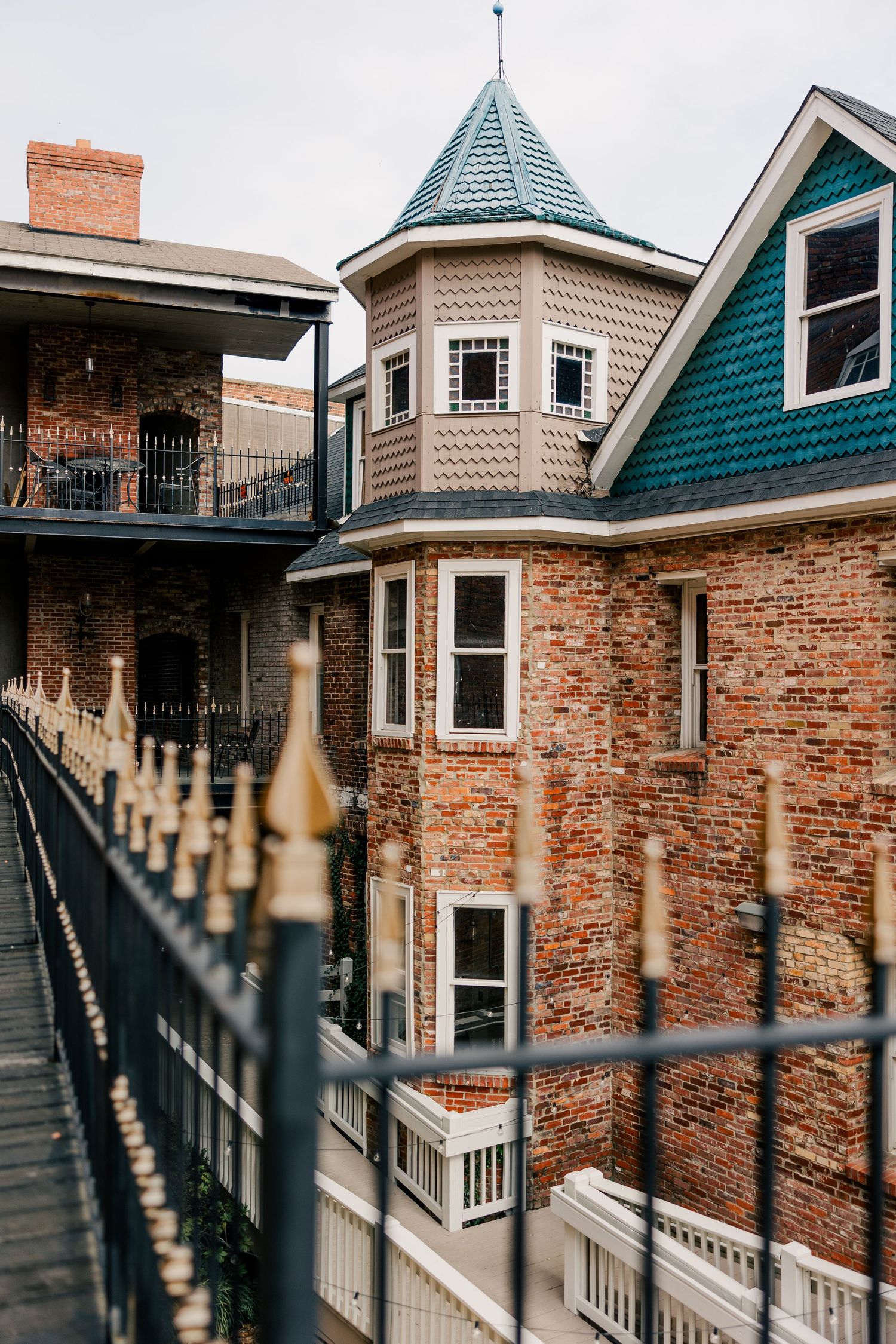 Historic brick building with ornate turret tower and Victorian architectural details viewed through decorative iron railings.