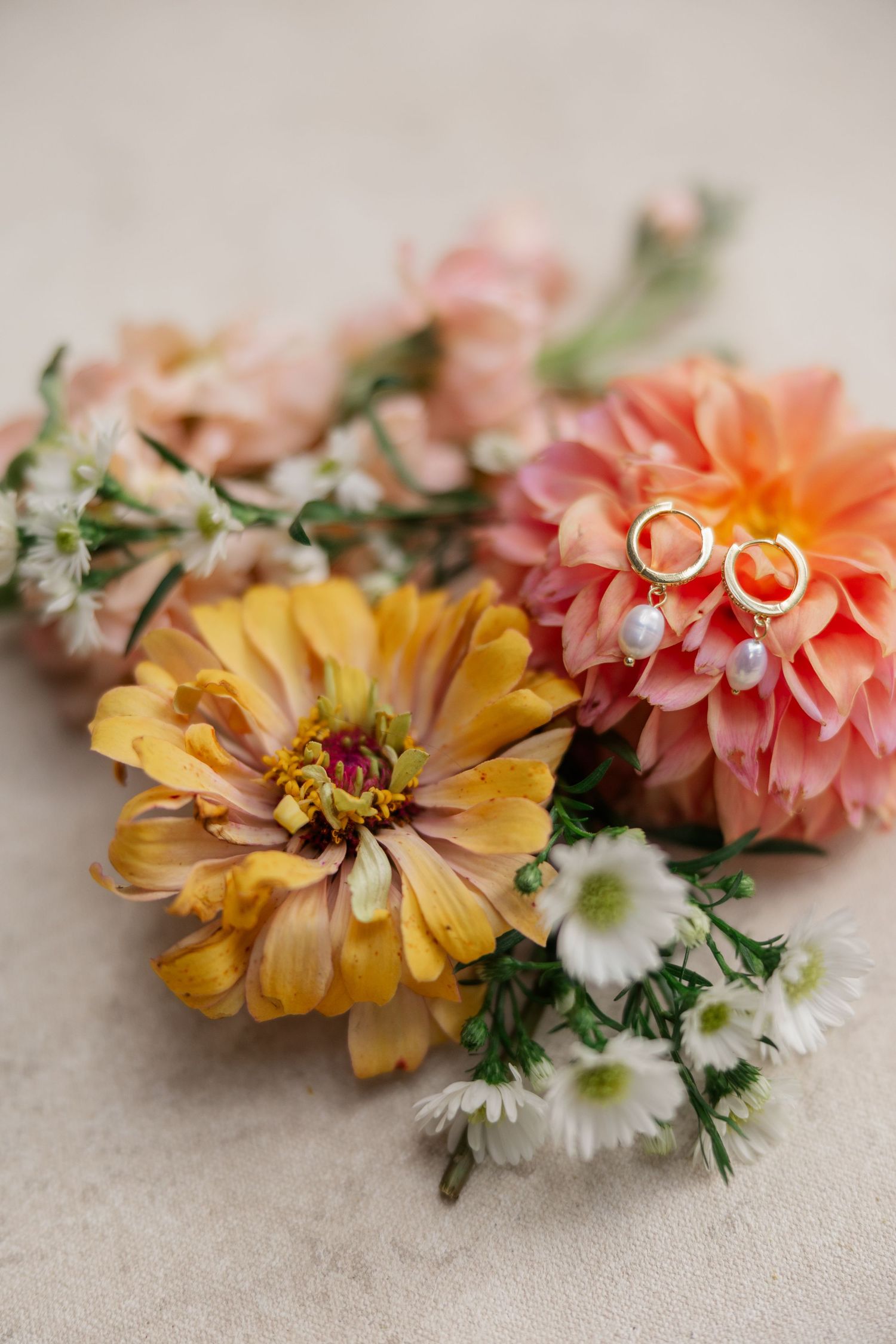 A delicate floral crown made with orange, pink and white dahlias and daisies arranged in a curved pattern. Parker Mill