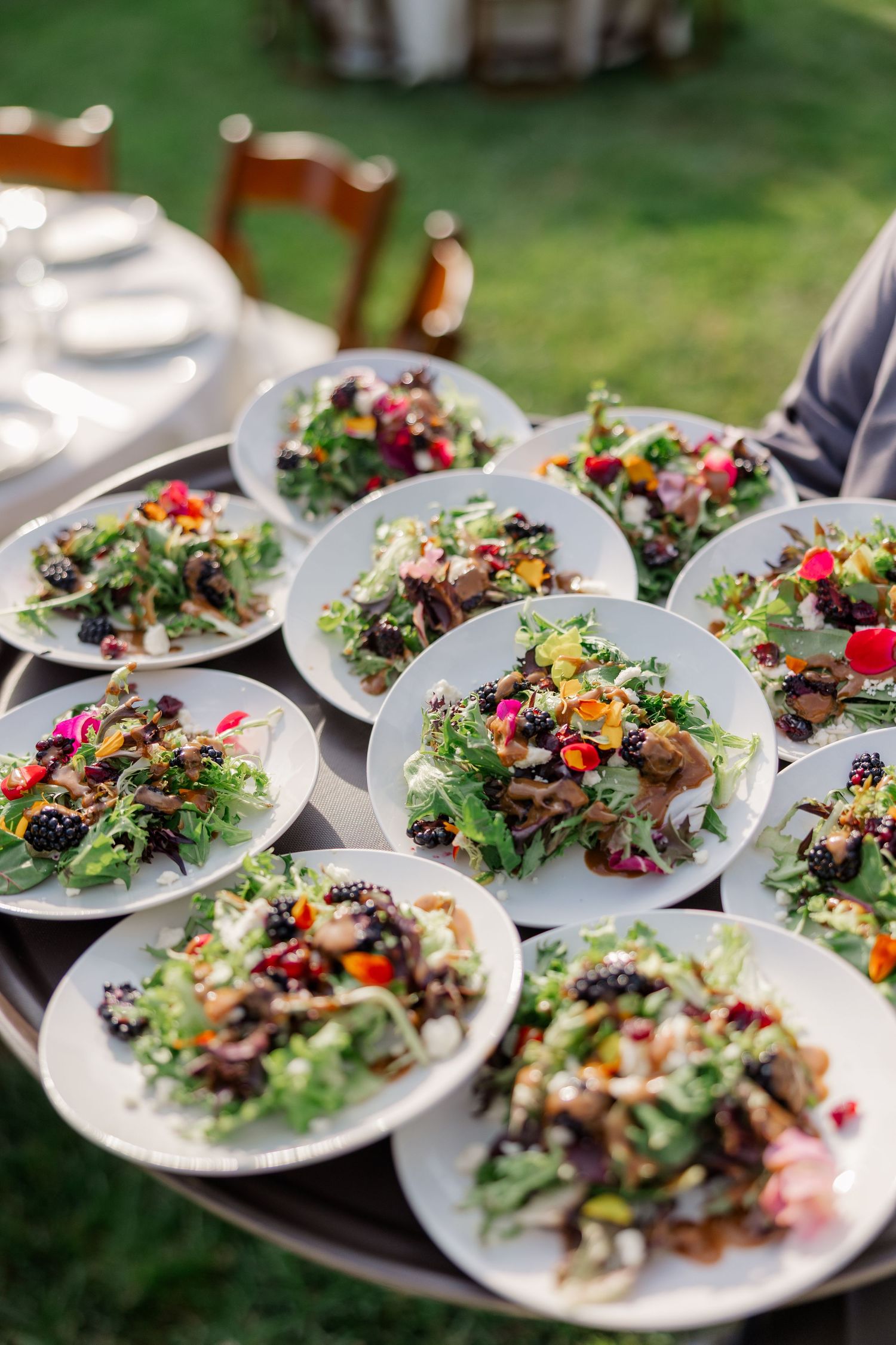 Beautifully plated garden salads with colorful edible flowers arranged on white plates for a wedding reception.
