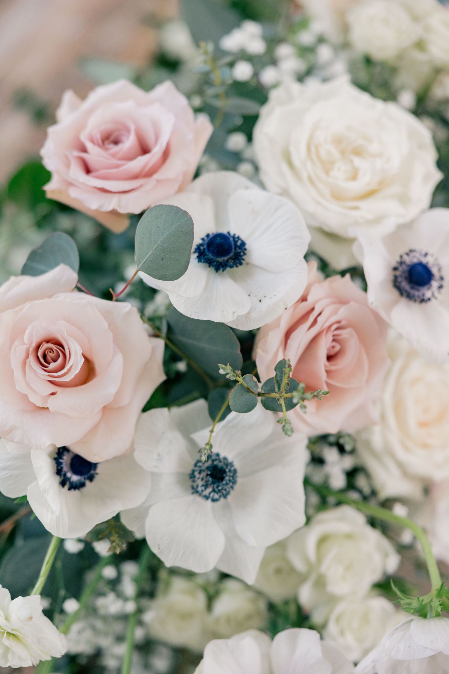 Elegant floral arrangement featuring blush pink roses and white anemones with navy centers.