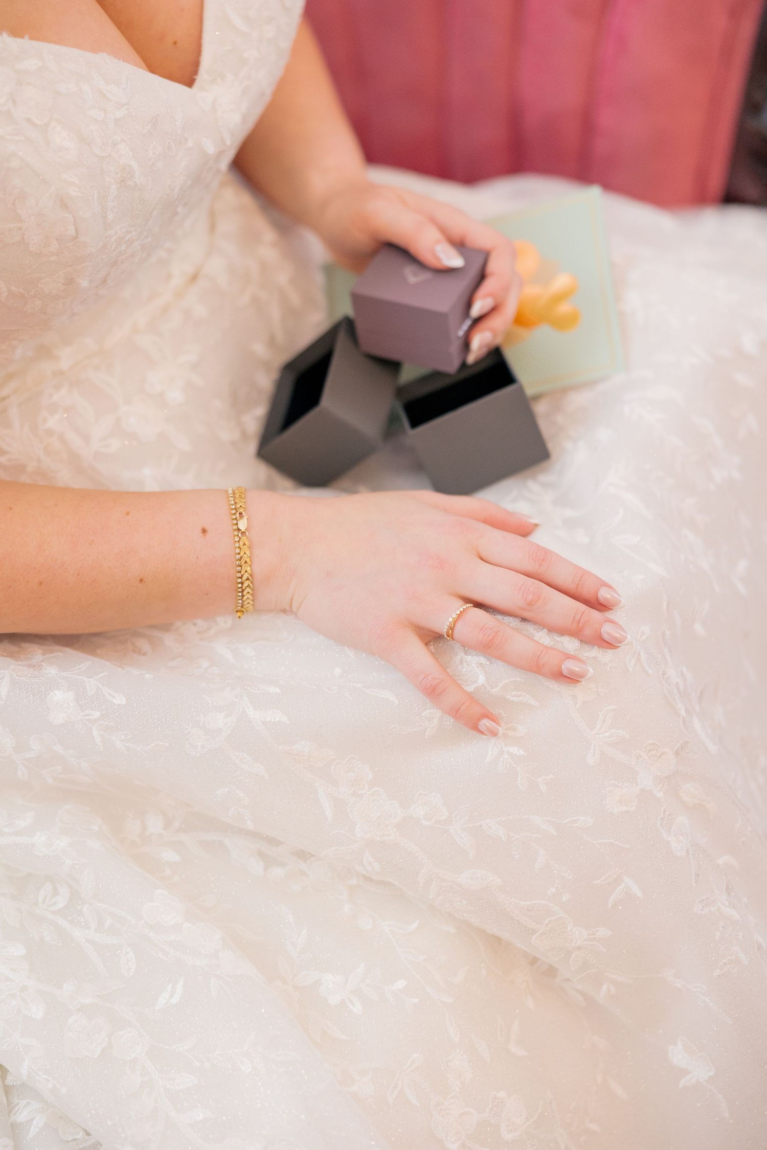 Close-up shot of hands delicately touching intricate lace details on a white wedding dress.
