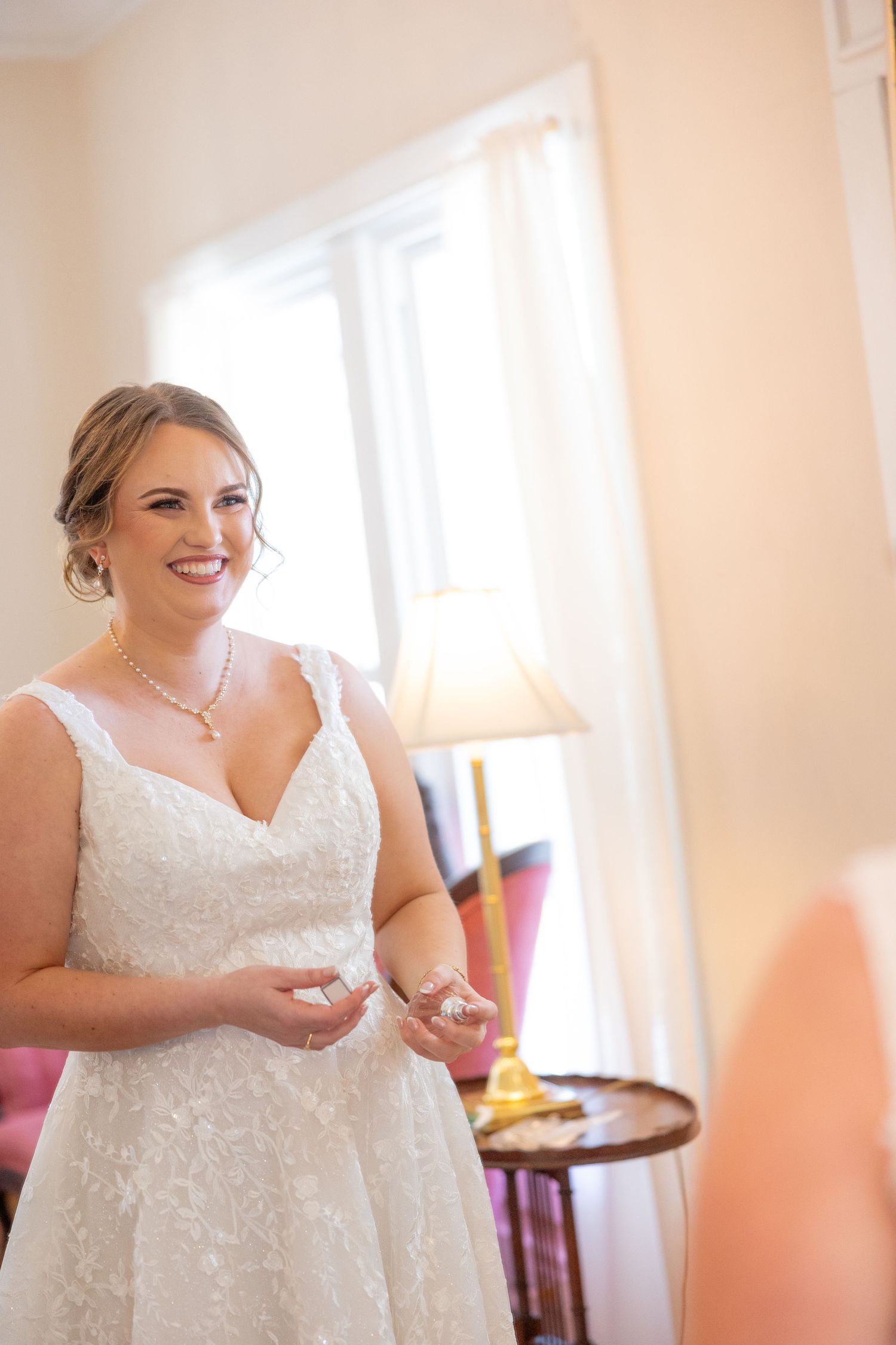 Bride getting ready in a beautiful white lace wedding dress with a V-neckline and beaded details.