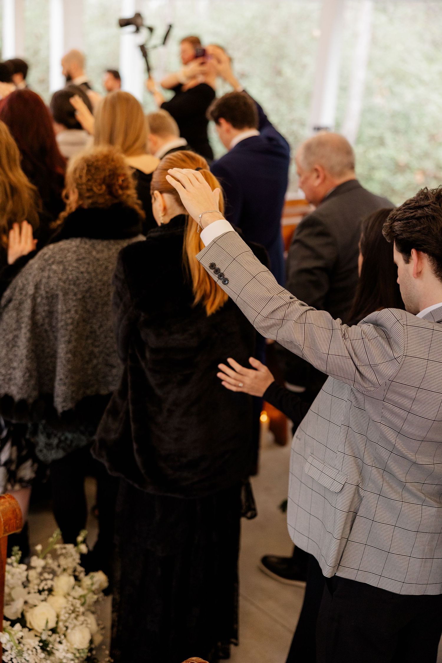 Wedding guests raise their hands in celebration during an indoor ceremony.