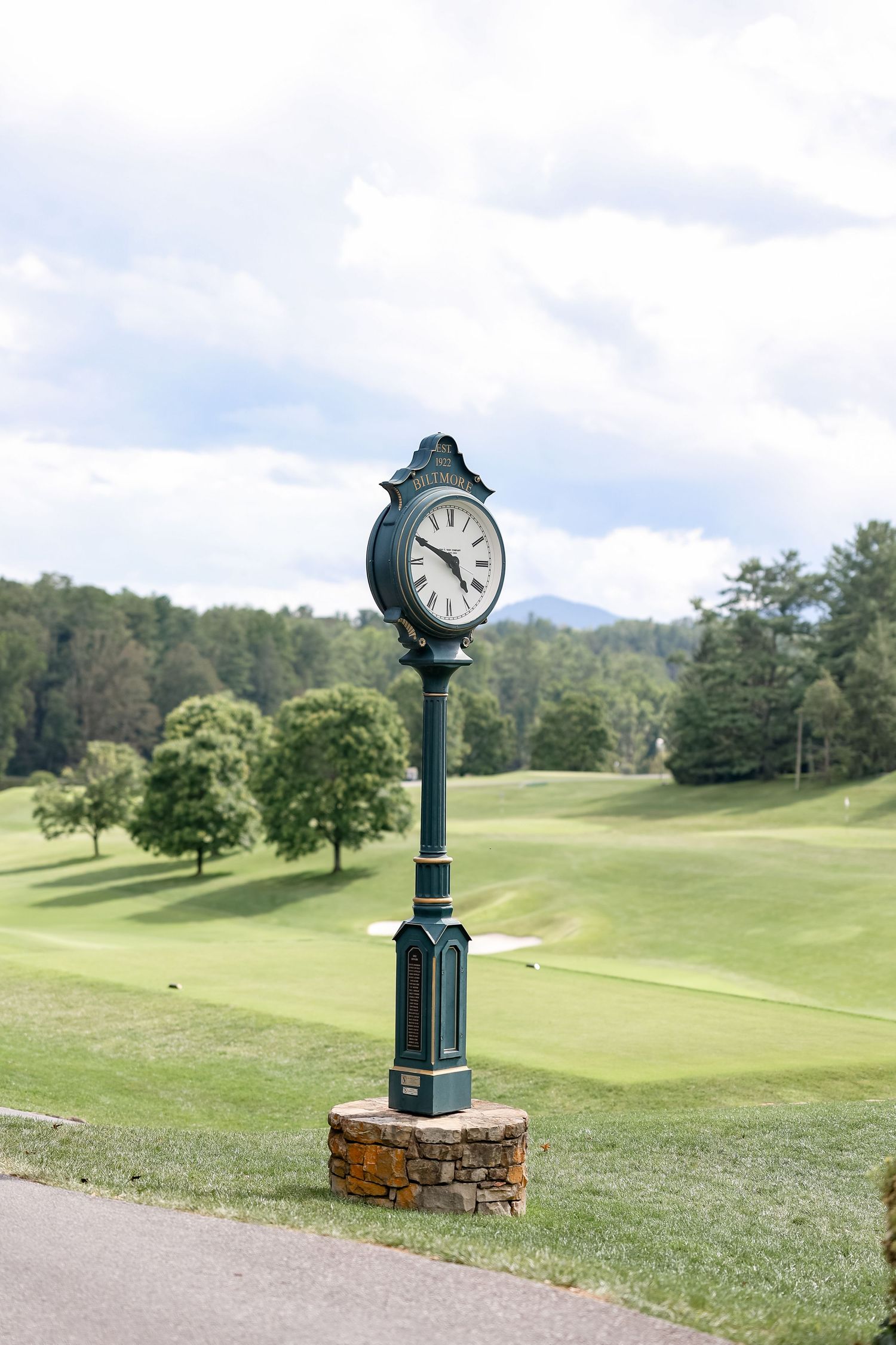 Vintage clock post standing on a lush green golf course with rolling hills in the background.
