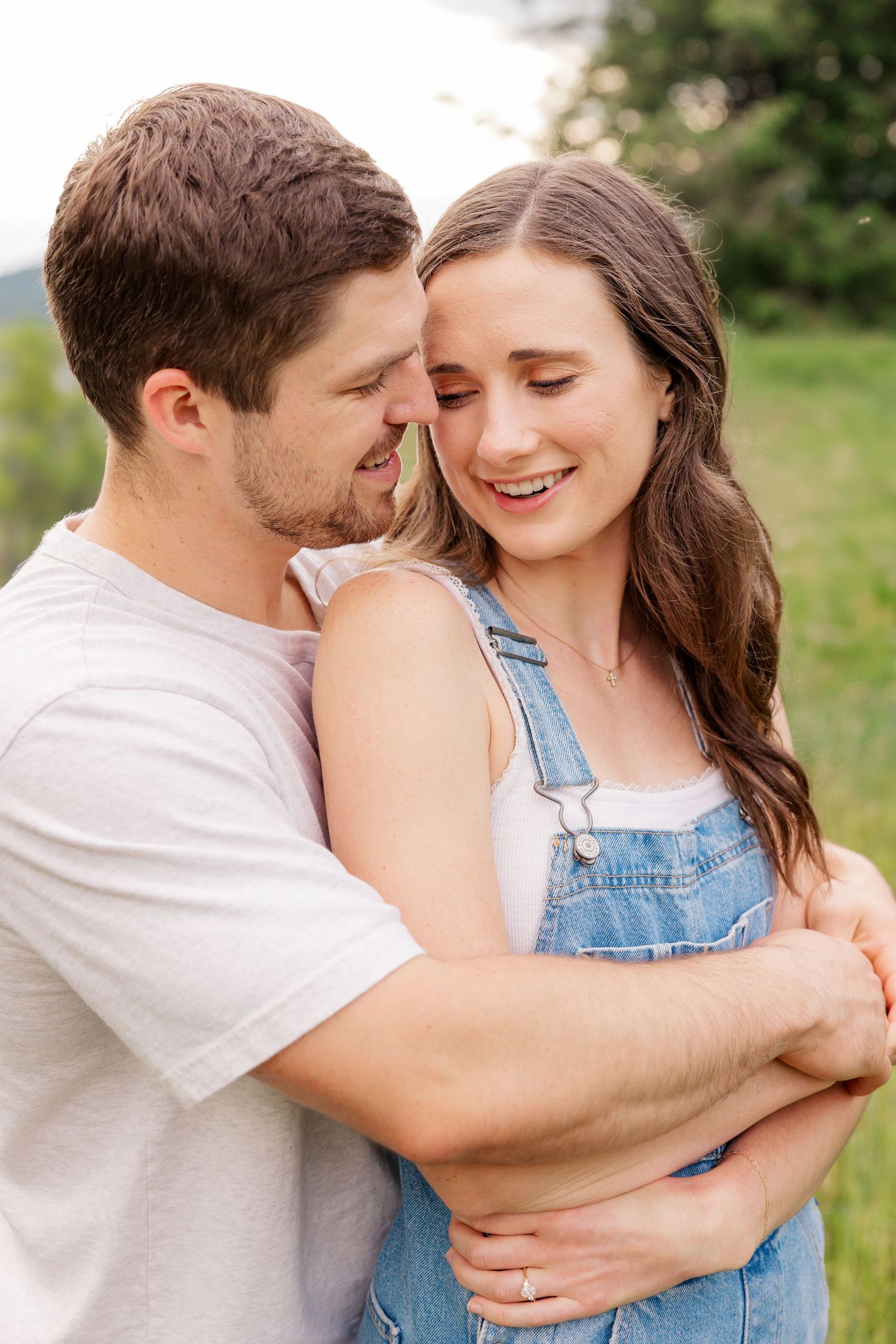 A tender moment between a couple in casual wear sharing an intimate embrace outdoors.