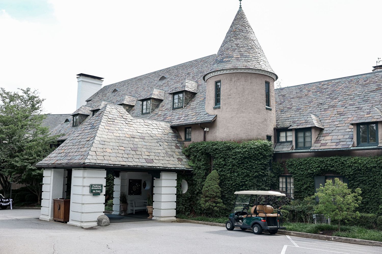 Biltmore Forest Country Club. Elegant country club entrance with stone turret, ivy-covered walls, and golf cart outside.