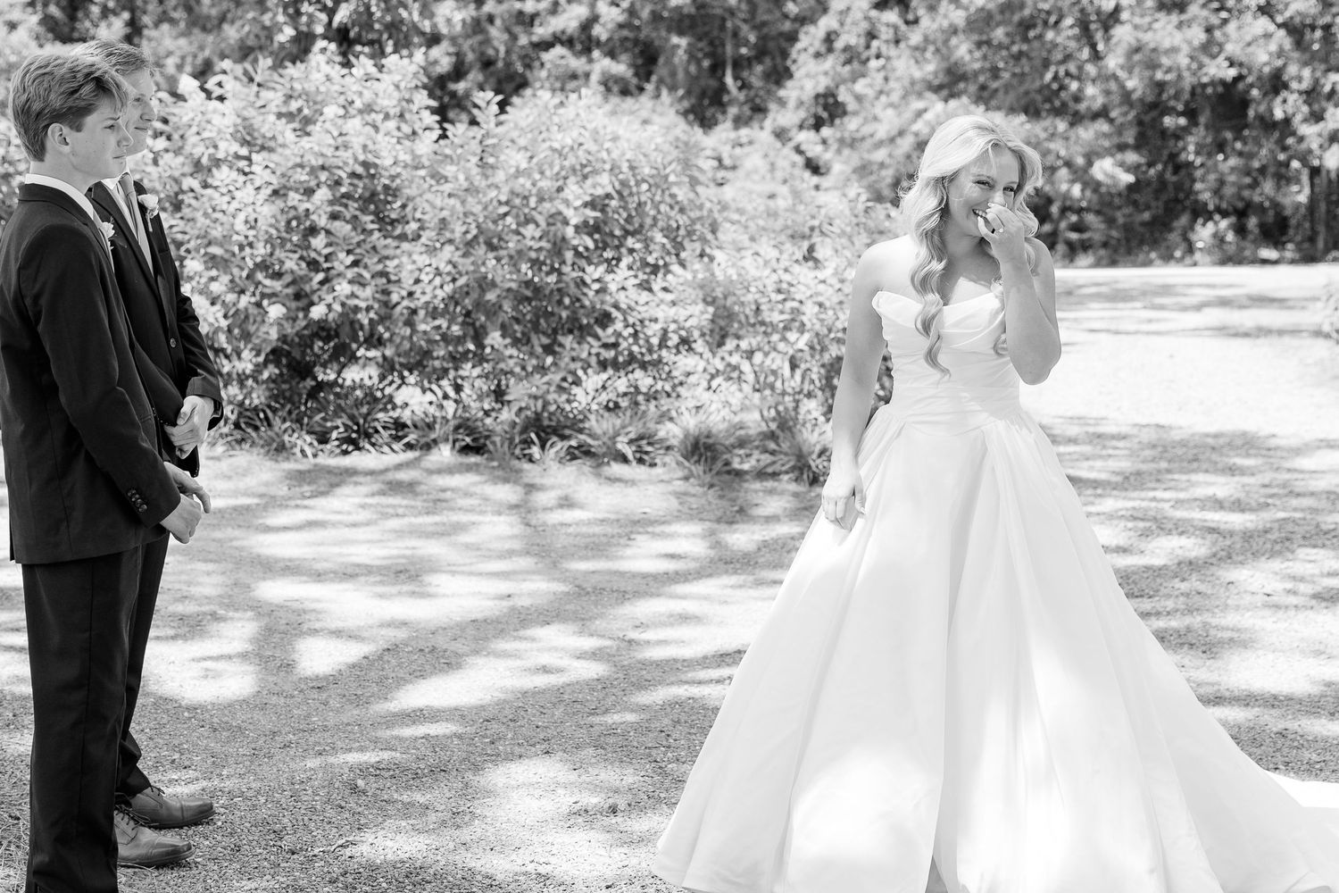 Black and white photo of a bride in a ballgown and groom in a suit sharing a first look outdoors.