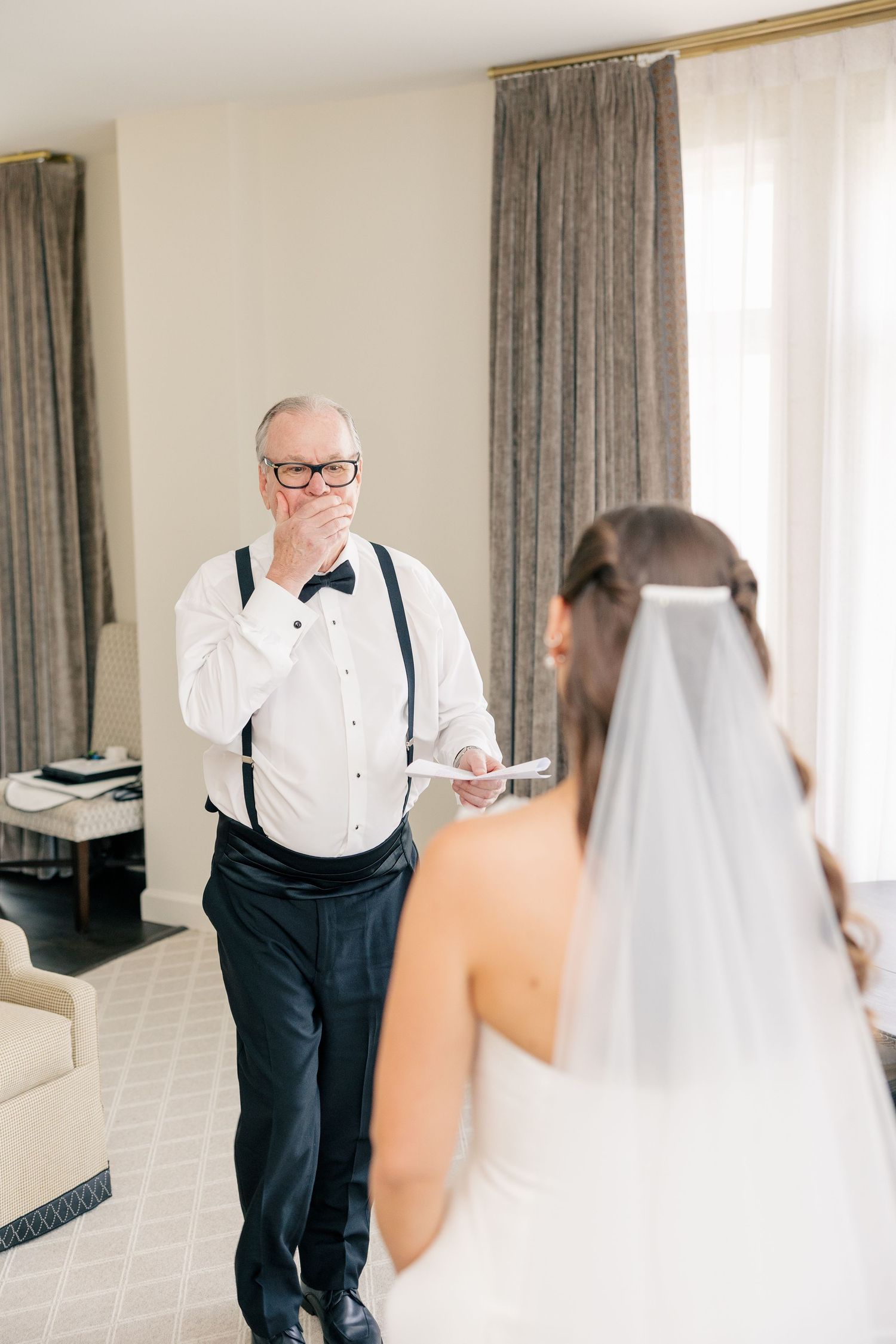 Tearful father in suspenders and bow tie sees his daughter in her wedding dress.