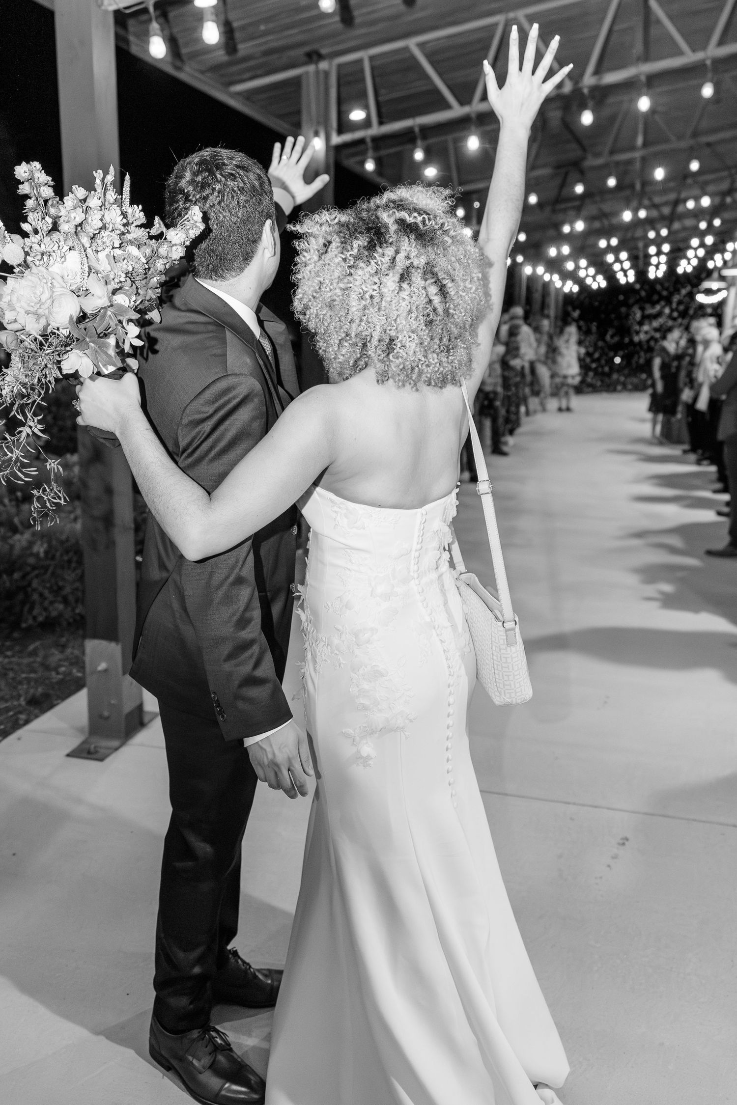 Black and white photo of bride and groom celebrating as they exit their wedding reception.