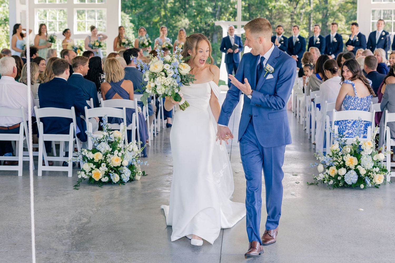 Bride and groom walking back down the aisle after wedding ceremony in elegant outdoor venue.