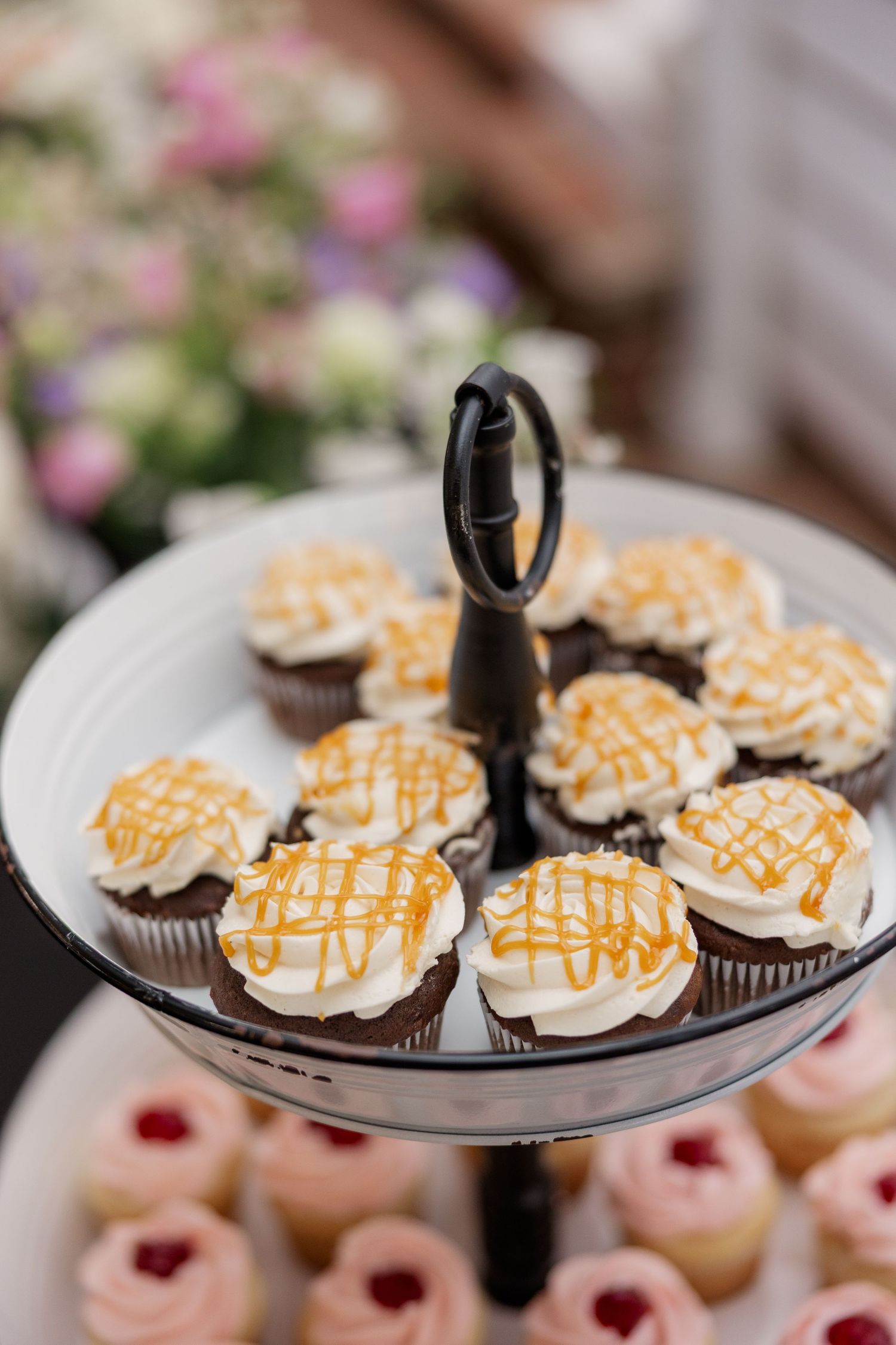 Dessert display featuring chocolate cupcakes with caramel drizzle and whipped cream on a white serving plate.