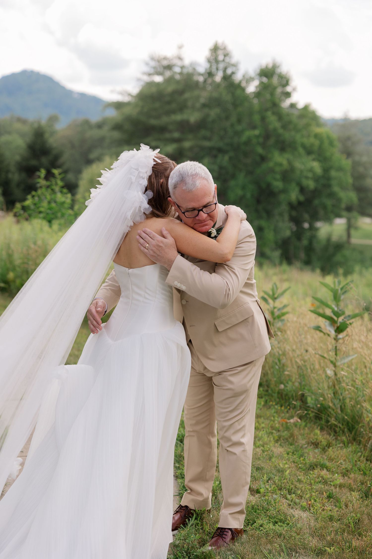 A touching moment captured during wedding photos in a scenic mountain setting.