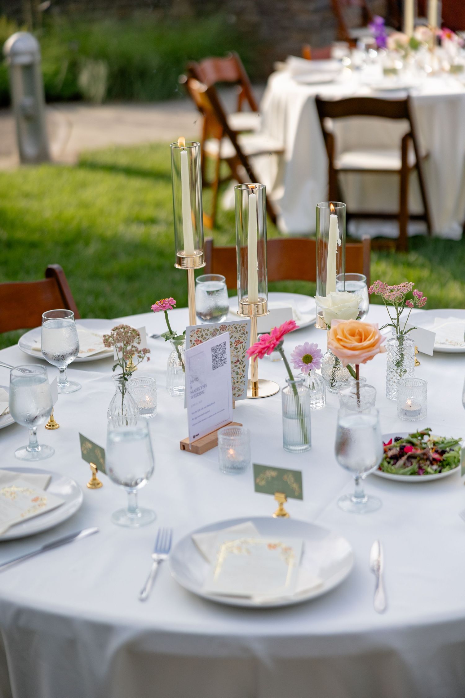 Elegant wedding reception tables set with white linens, candles, and delicate floral centerpieces.