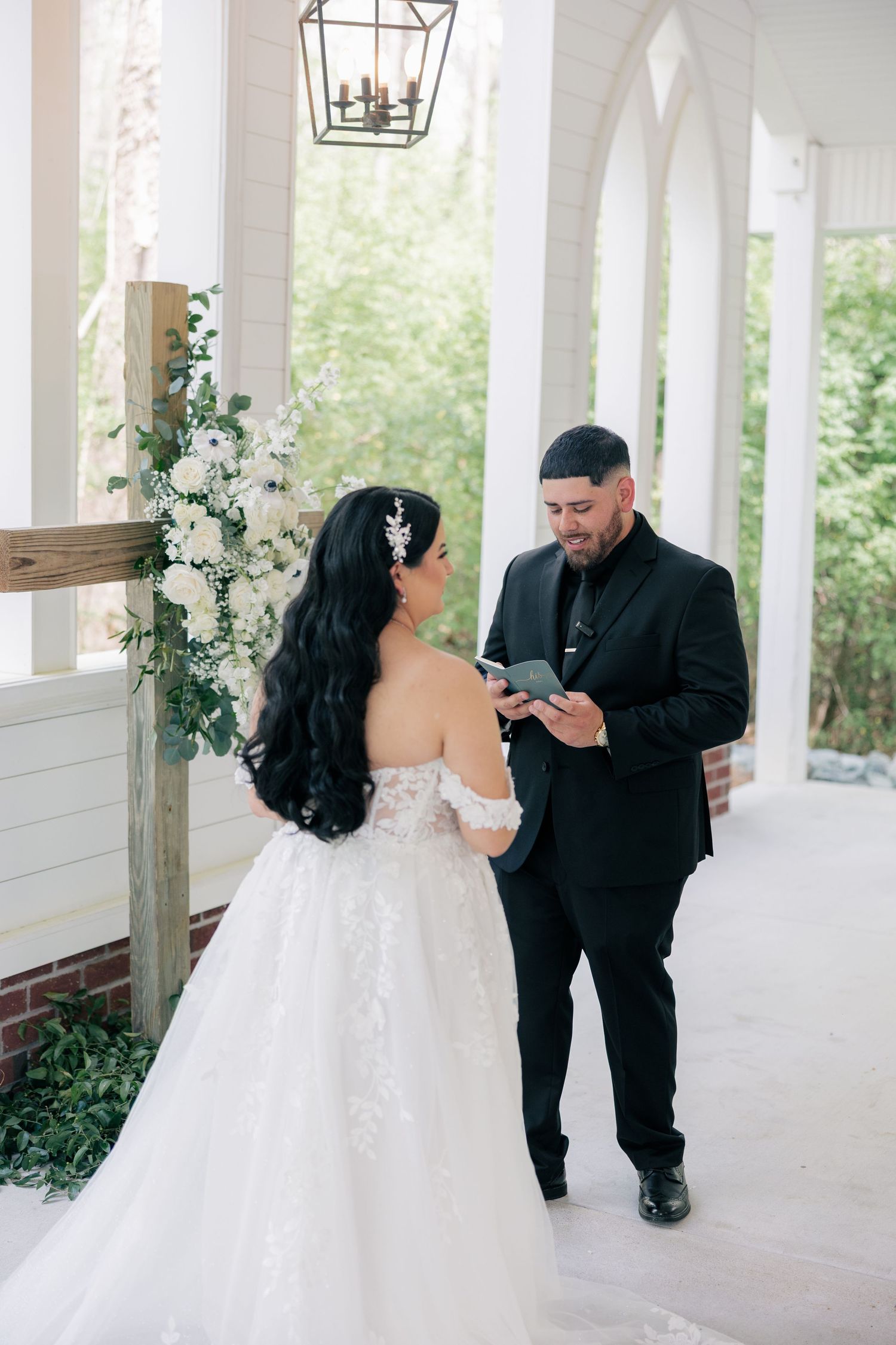 A special moment unfolds on a white columned porch during a wedding ceremony.