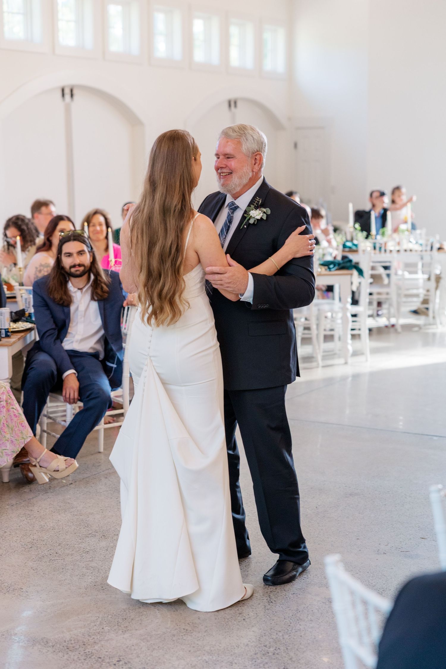 Wedding couple dances together in an elegant white reception venue.