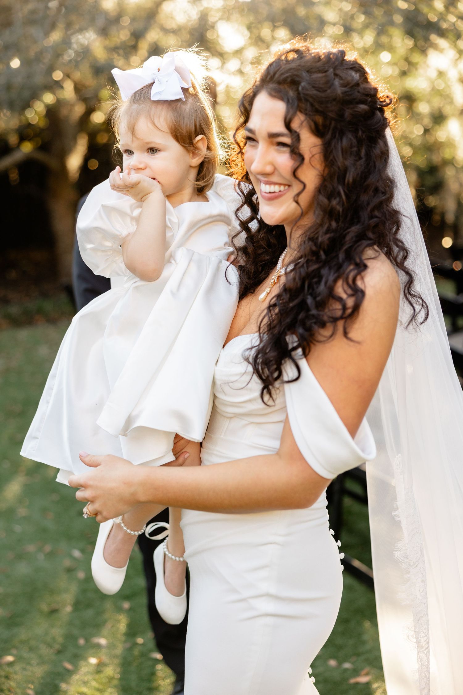 A heartwarming moment during a wedding photoshoot featuring beaming smiles and a white wedding gown outdoors.