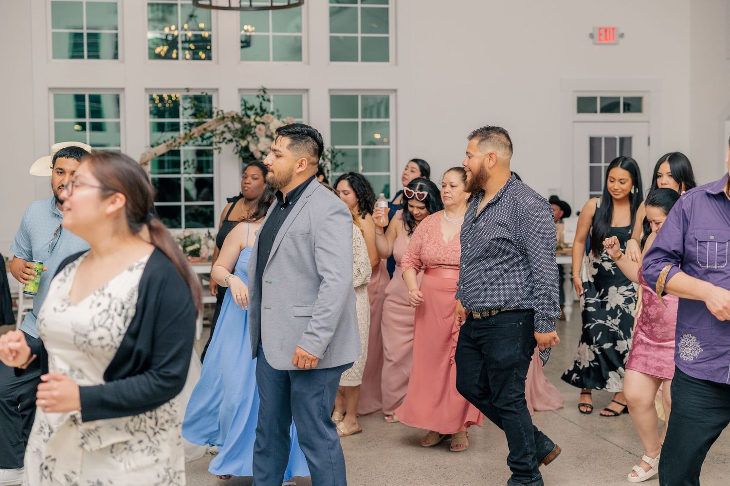Wedding reception guests dancing and mingling in an elegant indoor venue.