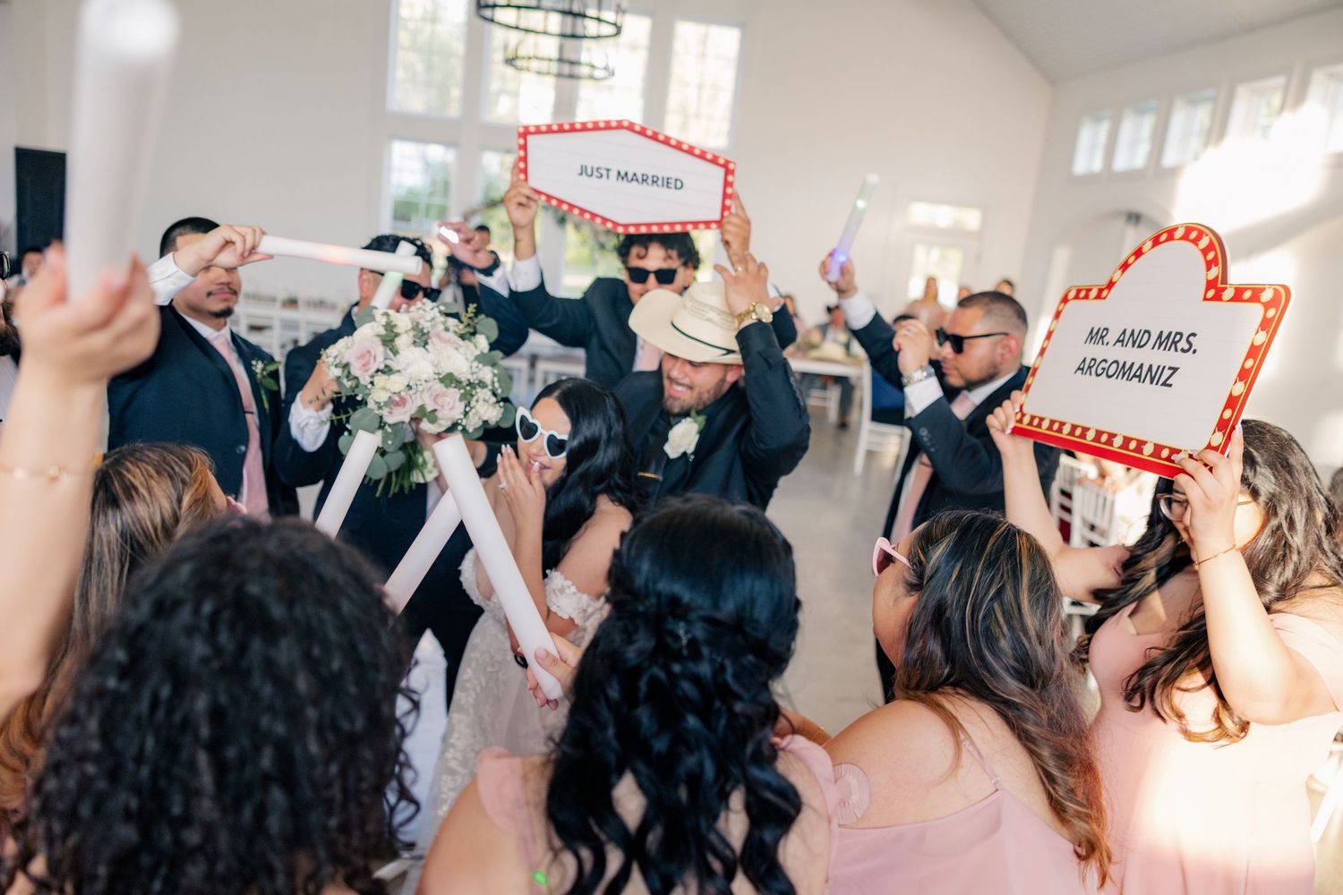Wedding guests celebrate and dance during a lively reception in an indoor venue.