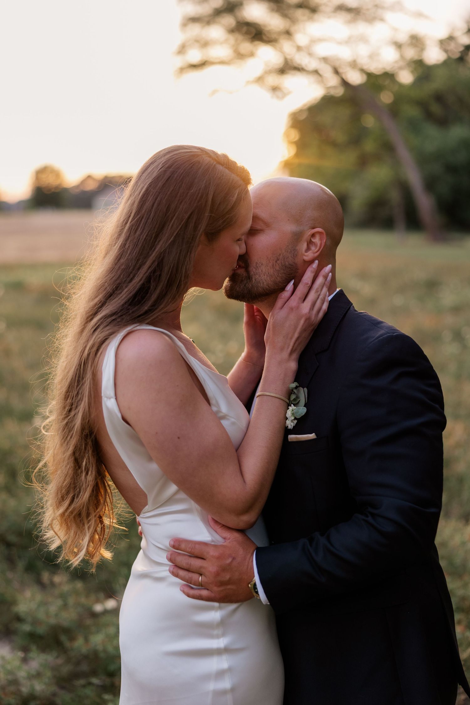 Romantic couple in formalwear sharing intimate kisses during an outdoor golden hour photo session.