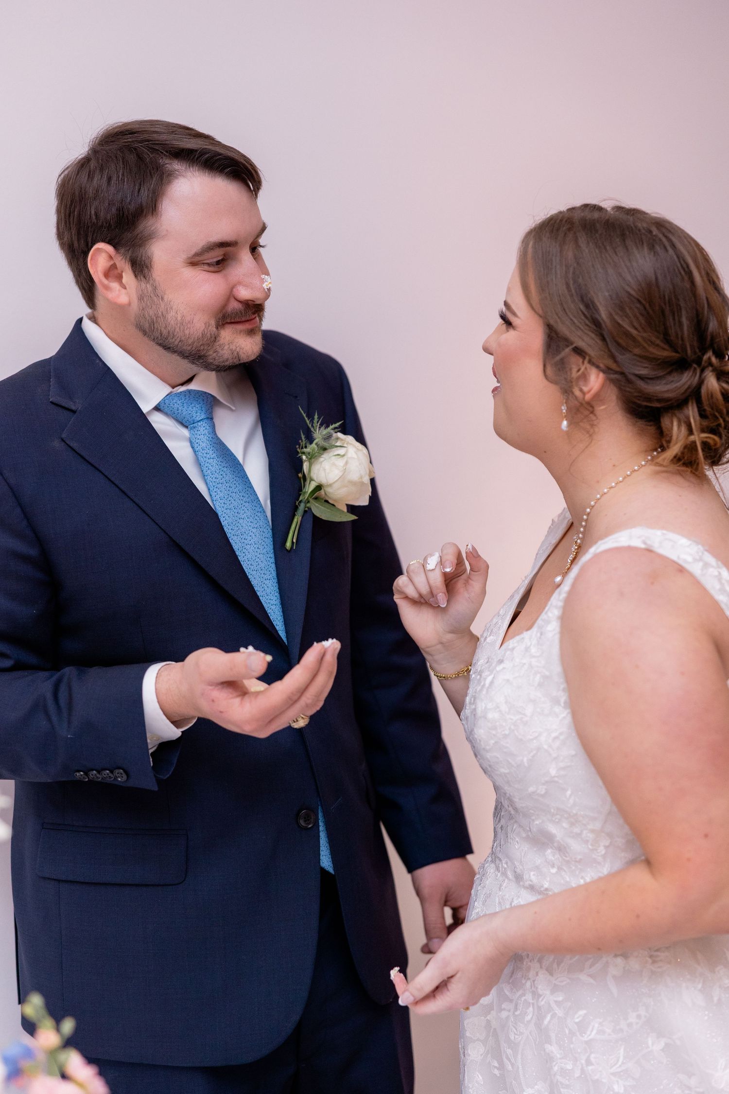 Candid moments between newlyweds during their first look against pink wall.