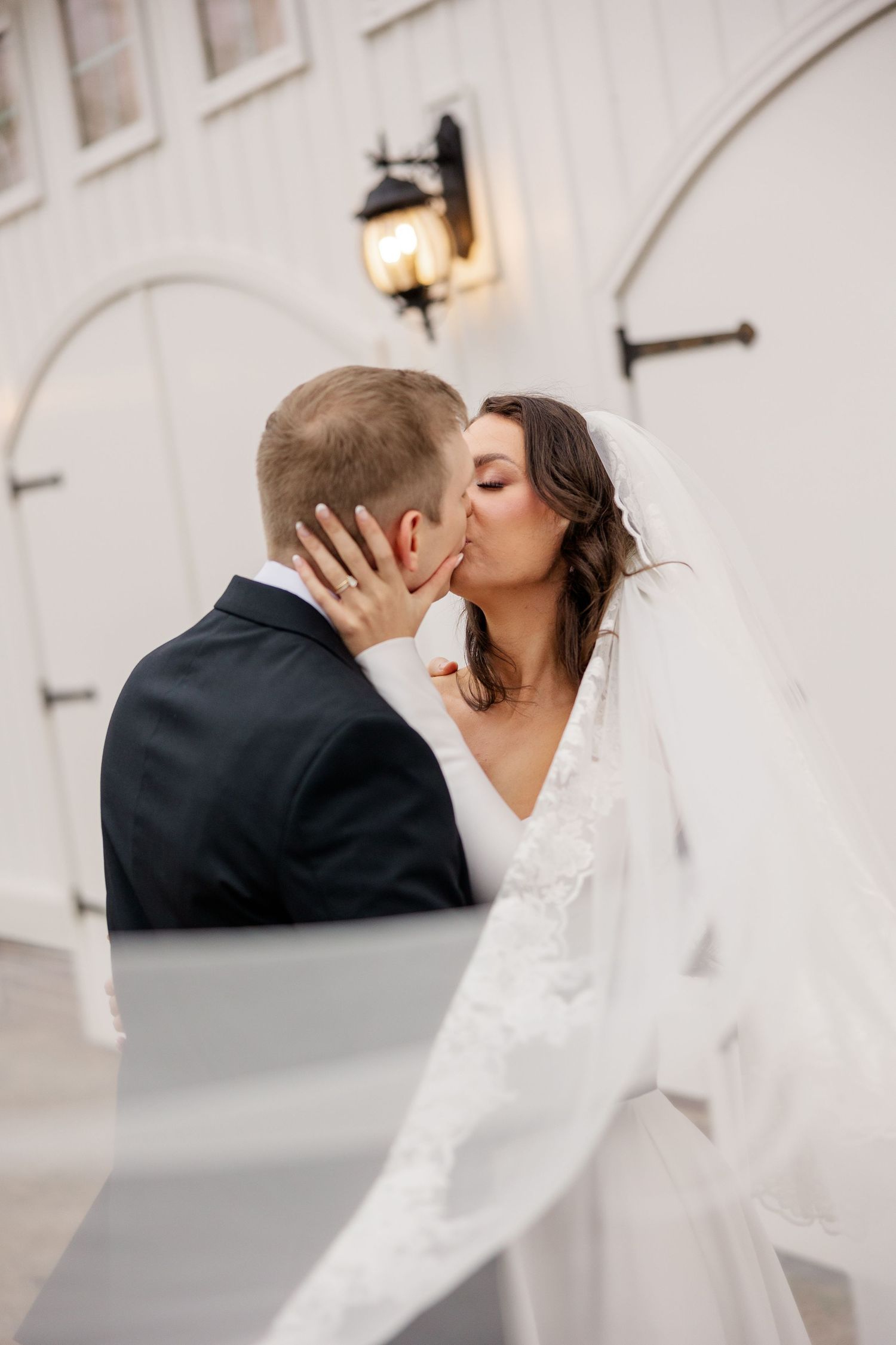 A romantic kiss shared against a white architectural backdrop.