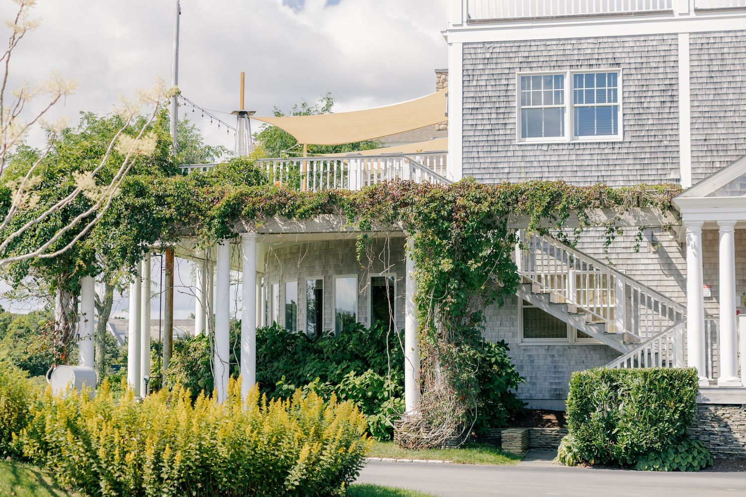 Charming wedding venue exterior with ivy-covered pergola, white railings, and lush garden landscaping.