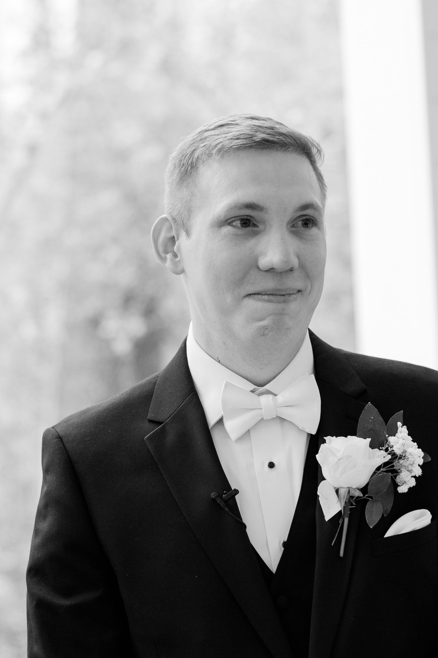 Classic black and white portrait of groom wearing tuxedo with white bowtie.