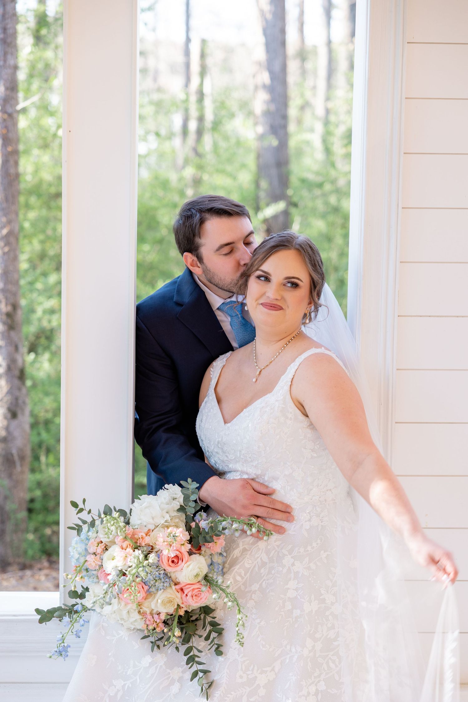Romantic wedding portraits captured on a white porch with soft pink floral bouquet.