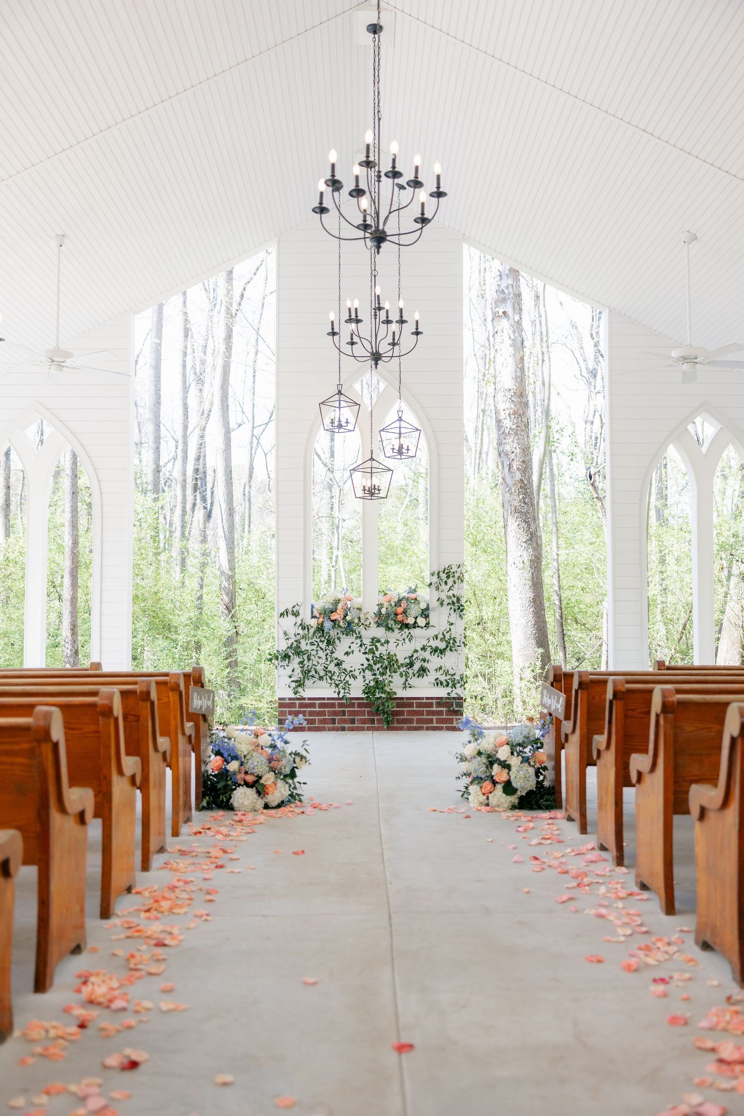 Church wedding ceremony setup with wooden pews and rose petals lining the aisle.