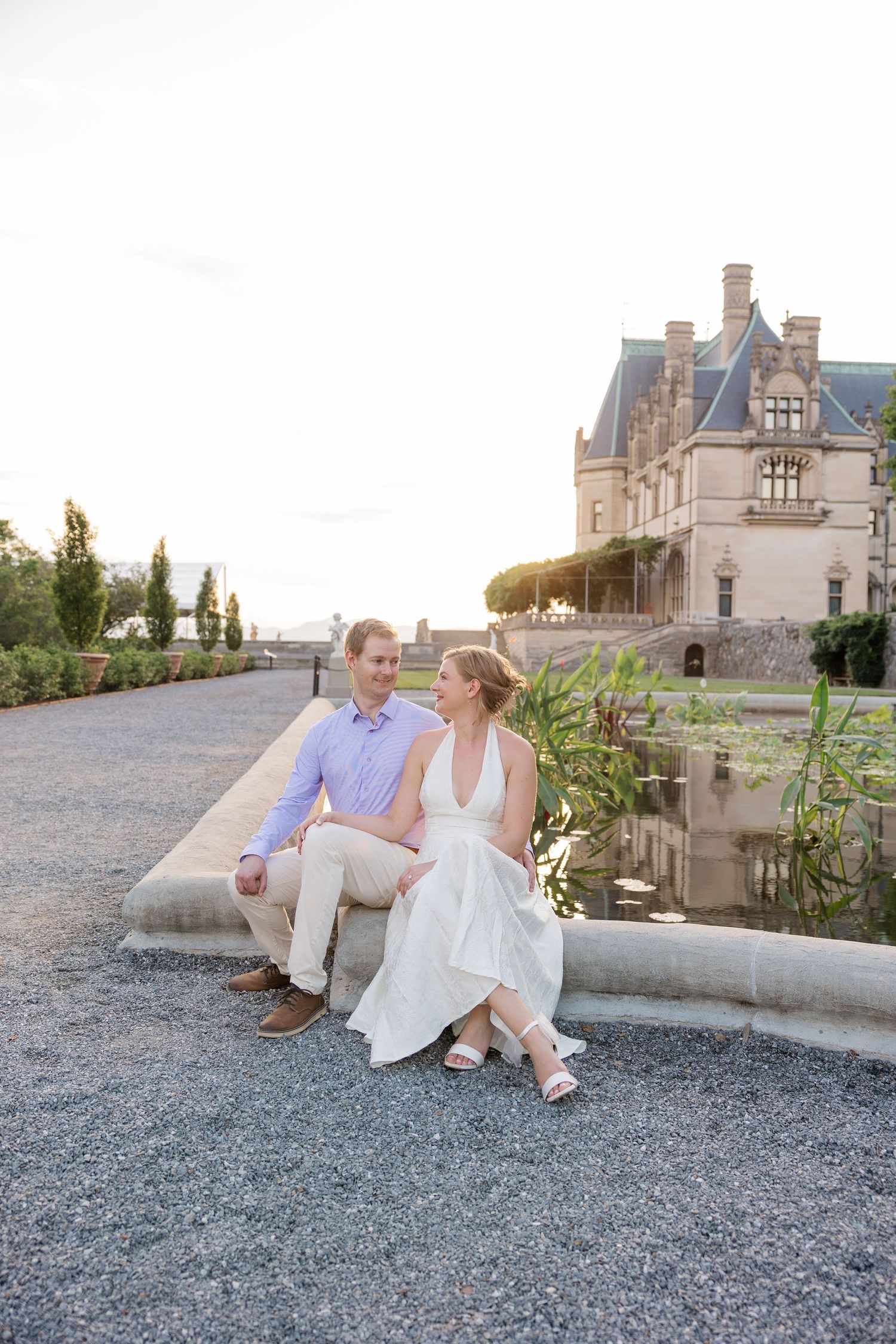 A couple enjoying a romantic moment while sitting on stone steps at a beautiful chateau in the late afternoon light.