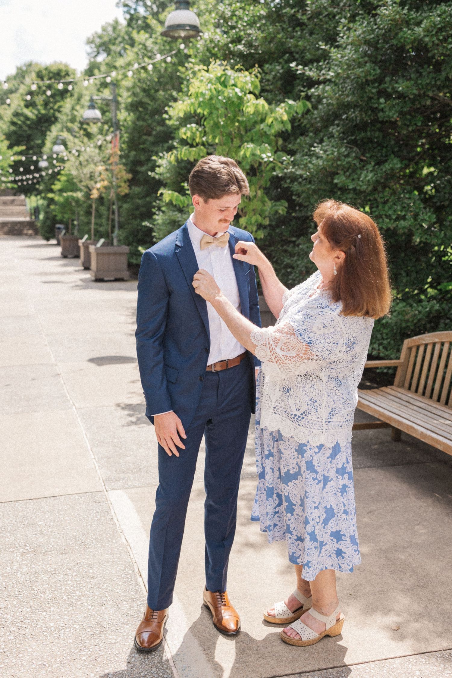 A couple shares a joyful dance moment together on a paved outdoor patio surrounded by greenery.