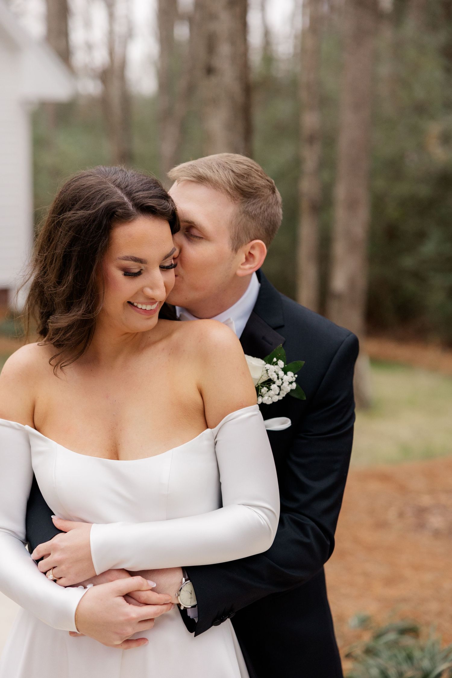 A tender wedding moment captured with a couple embracing in an intimate pose against a forest backdrop.