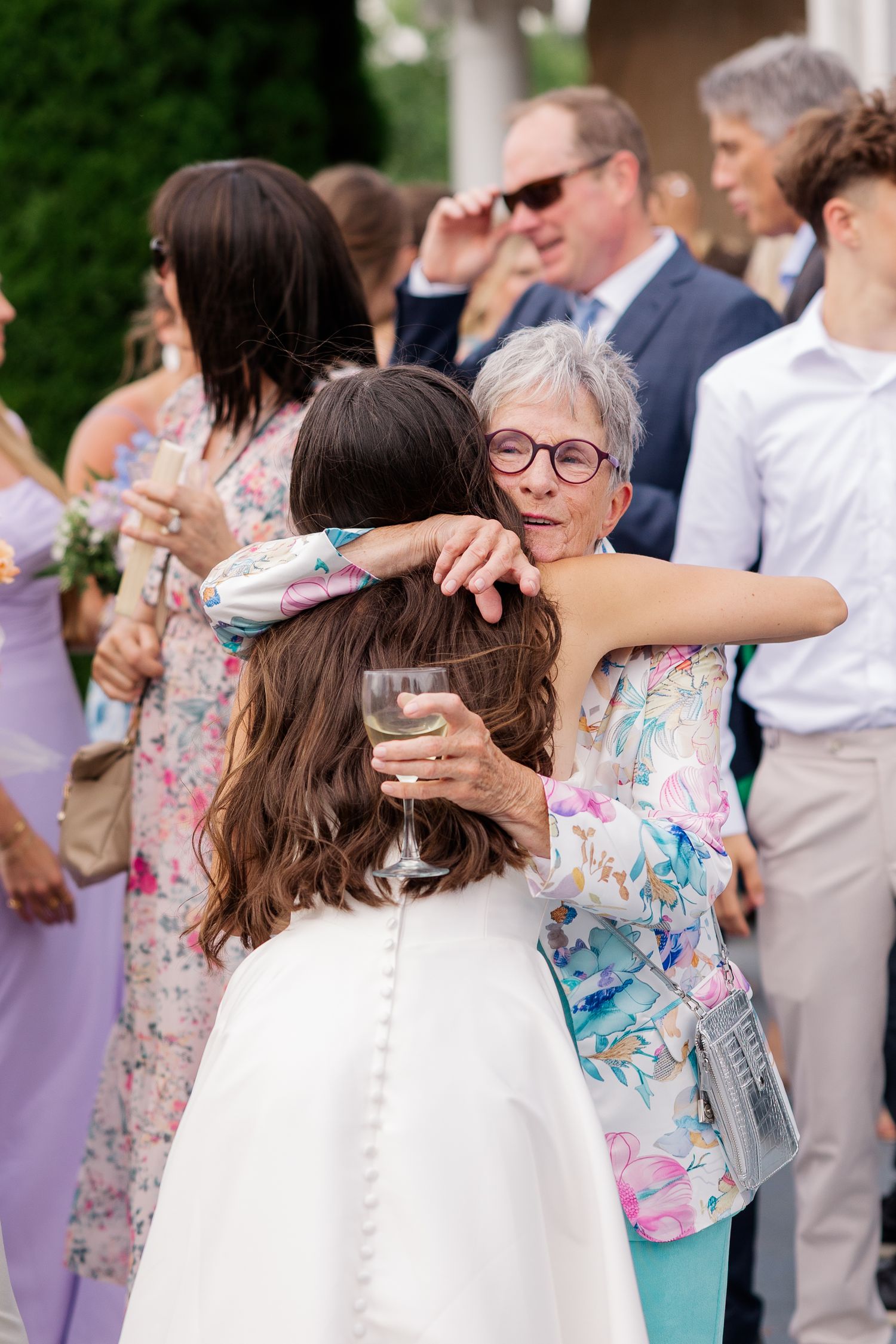 Wedding guests celebrate and dance together at an outdoor reception with floral dresses.