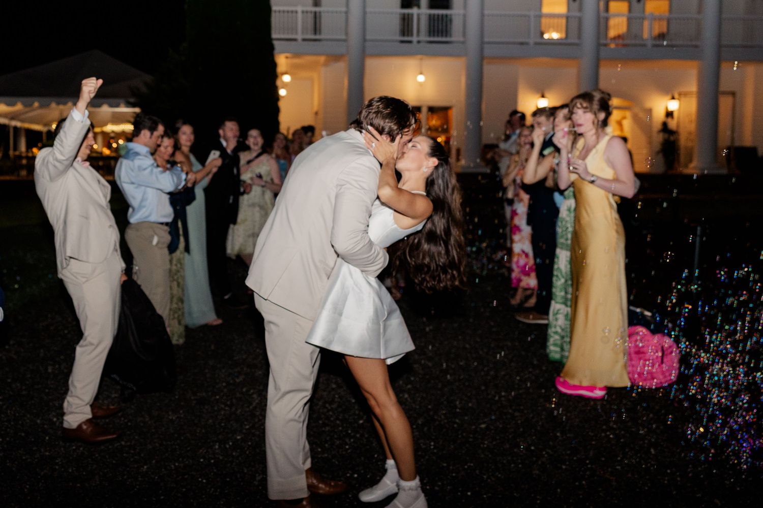 Wedding guests dance outside at night during a festive outdoor reception.