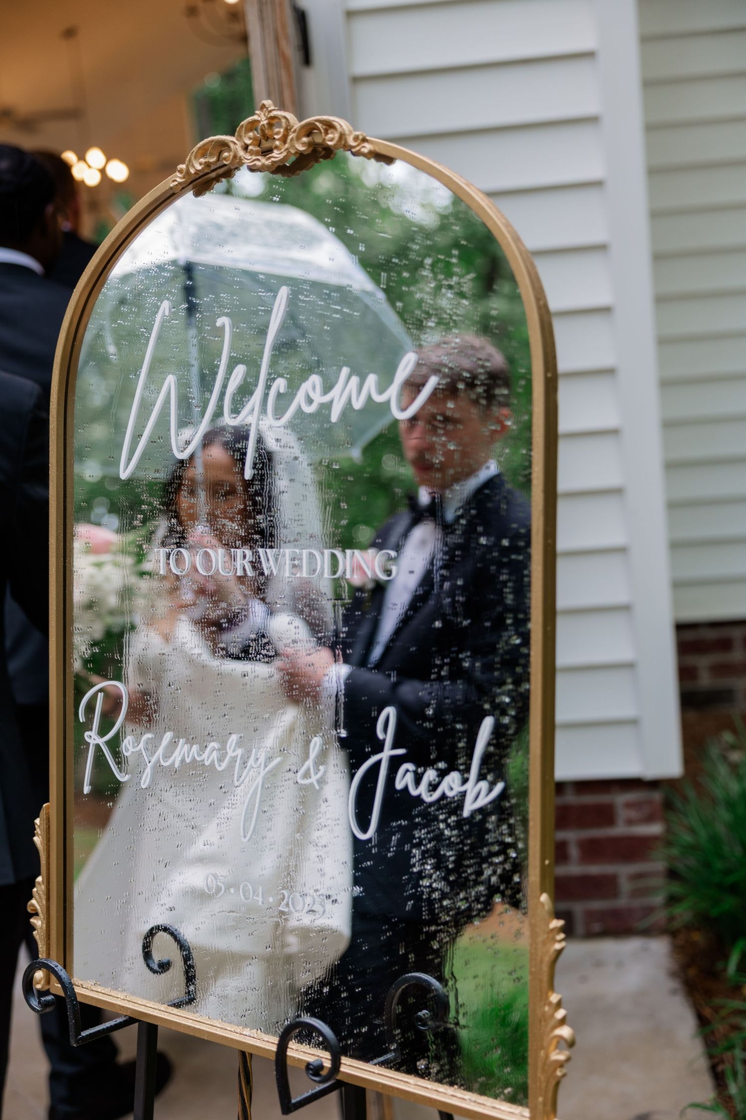 An elegant gold-framed welcome mirror sign displayed at a wedding ceremony.