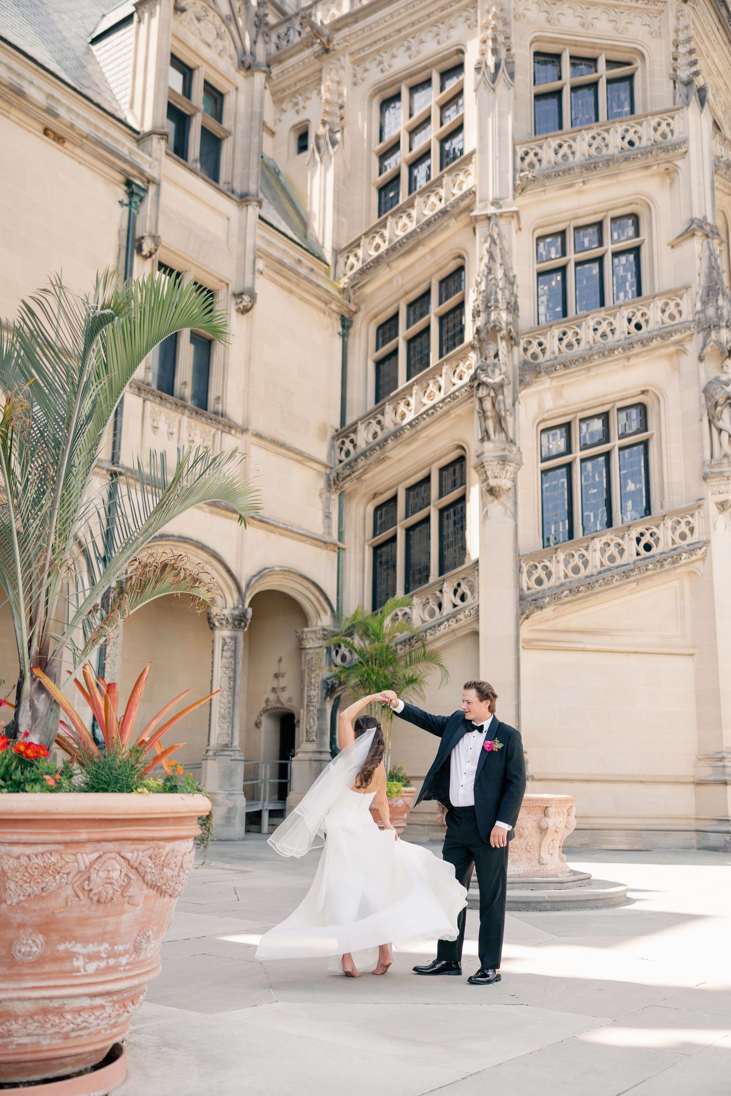 Bride and groom dancing in courtyard of ornate historic castle mansion on their wedding day.