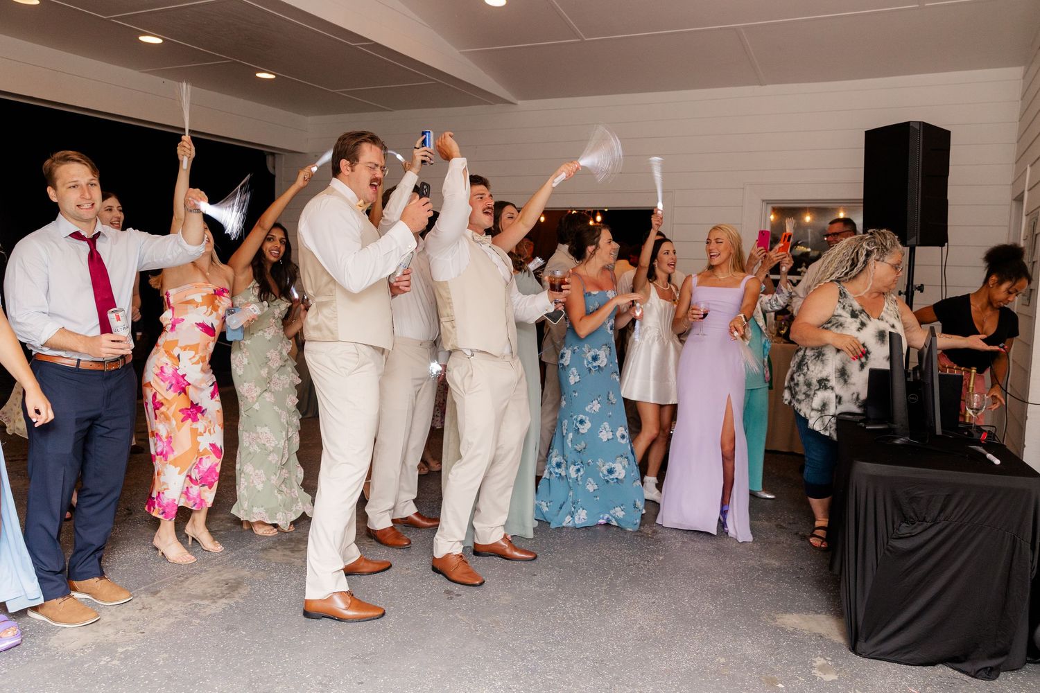 Wedding party dancing and celebrating in indoor reception venue.