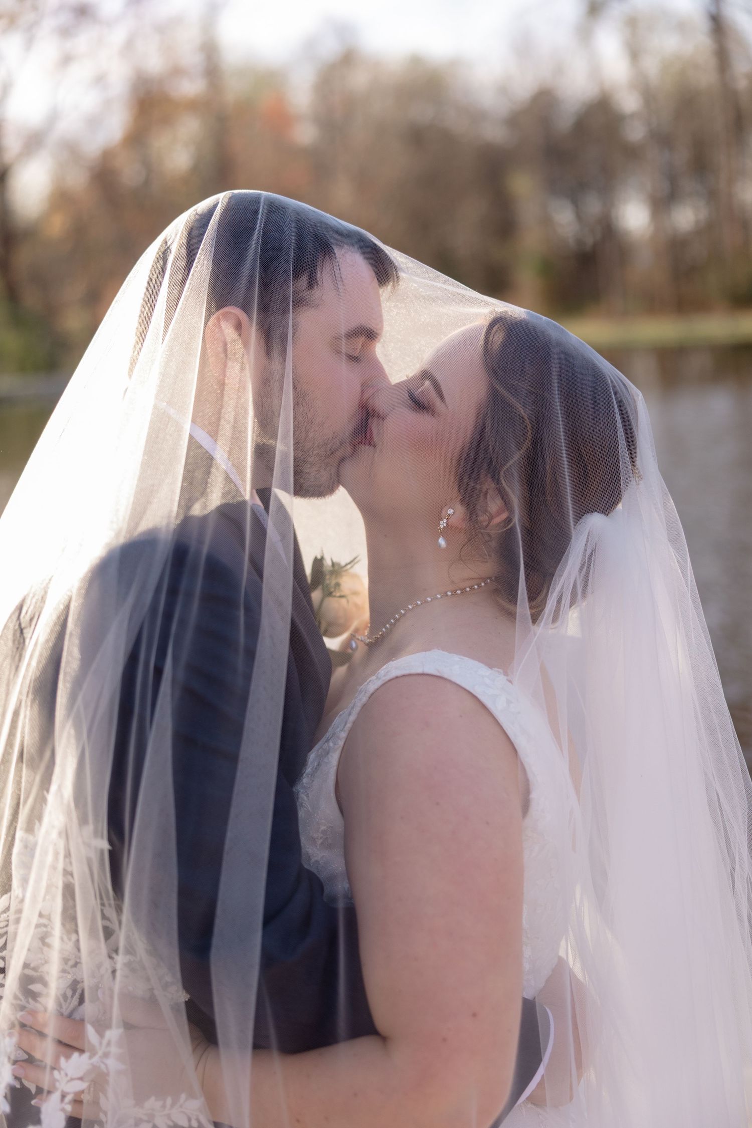 Romantic moment captured under wedding veil during outdoor photo session.