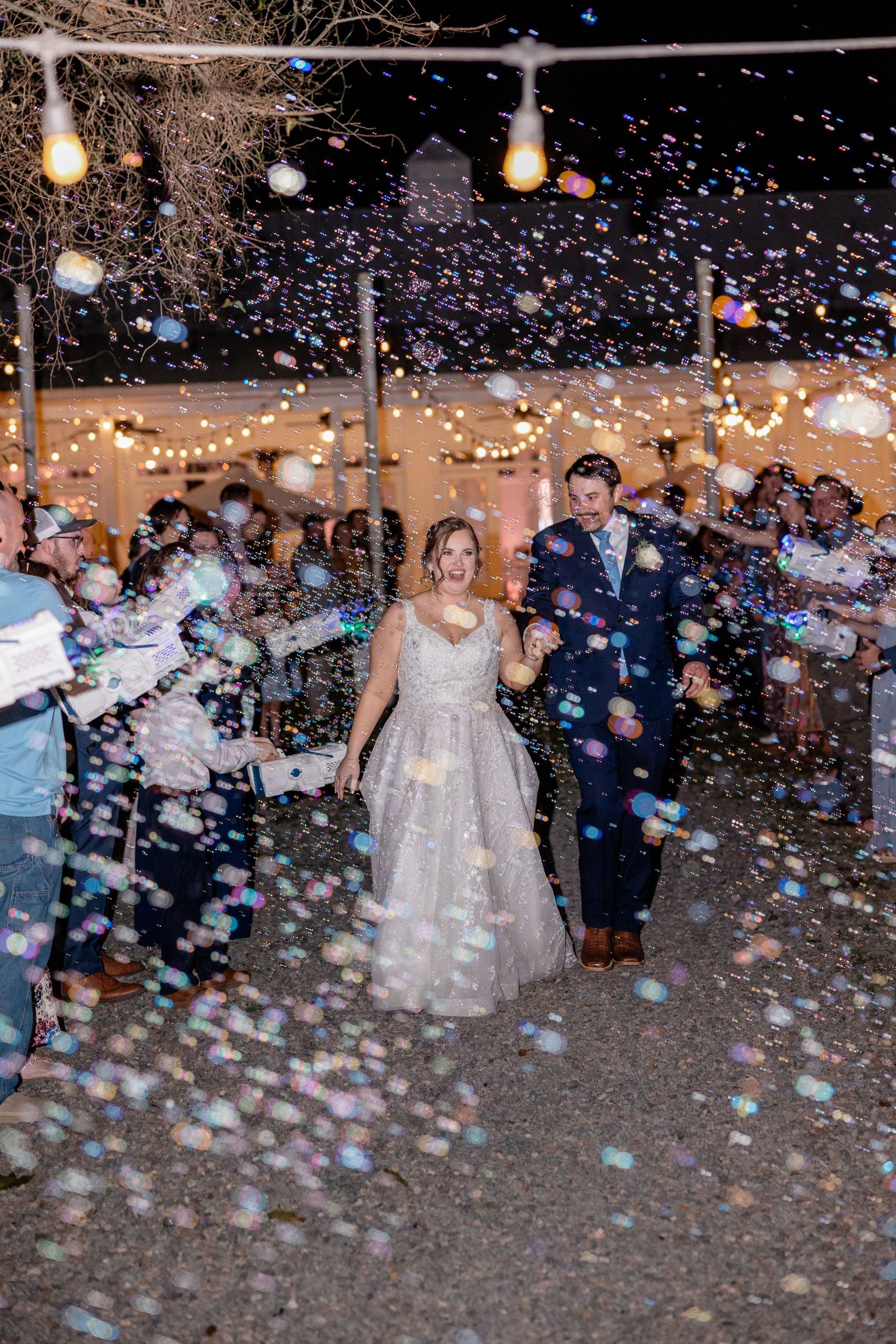 Wedding celebration finale with confetti falling under twinkling lights at night.