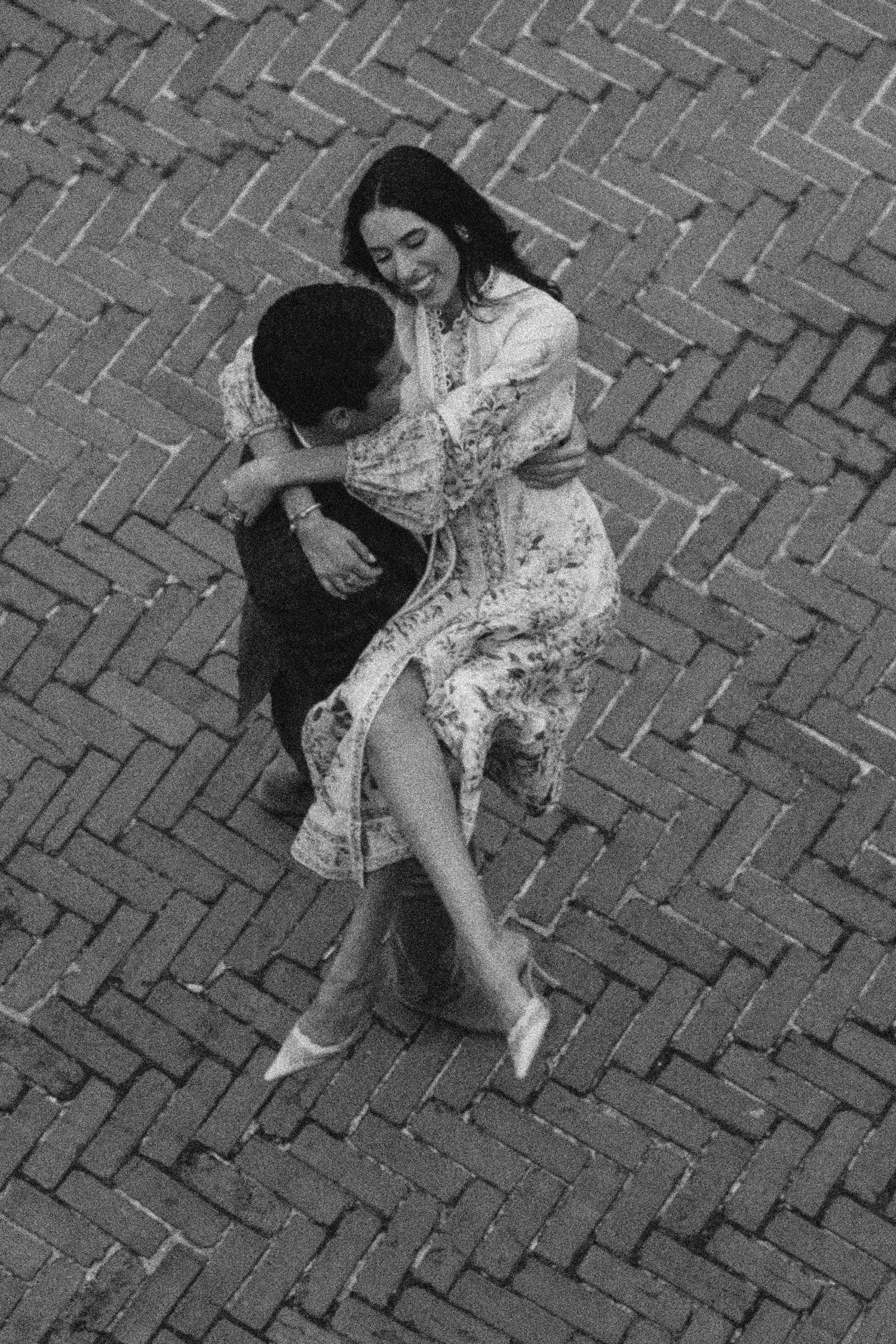A black and white overhead shot of two dancers performing on a herringbone brick floor.