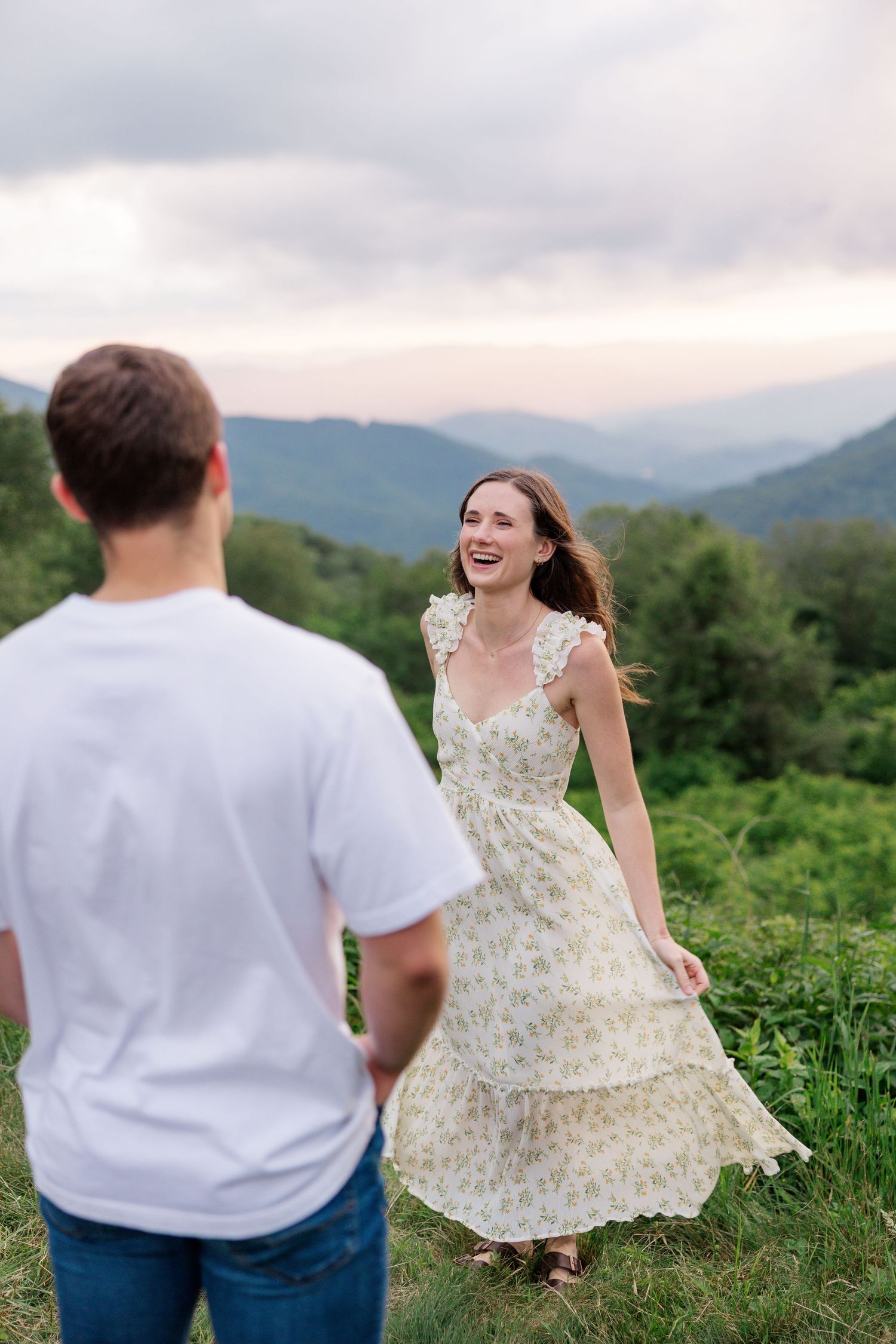 A couple shares joyful moments together in a mountain field during golden hour.