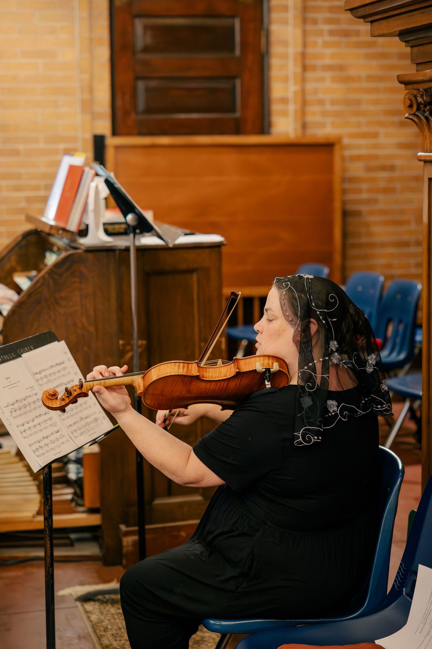 Violinist in black attire performing at wedding ceremony inside church.