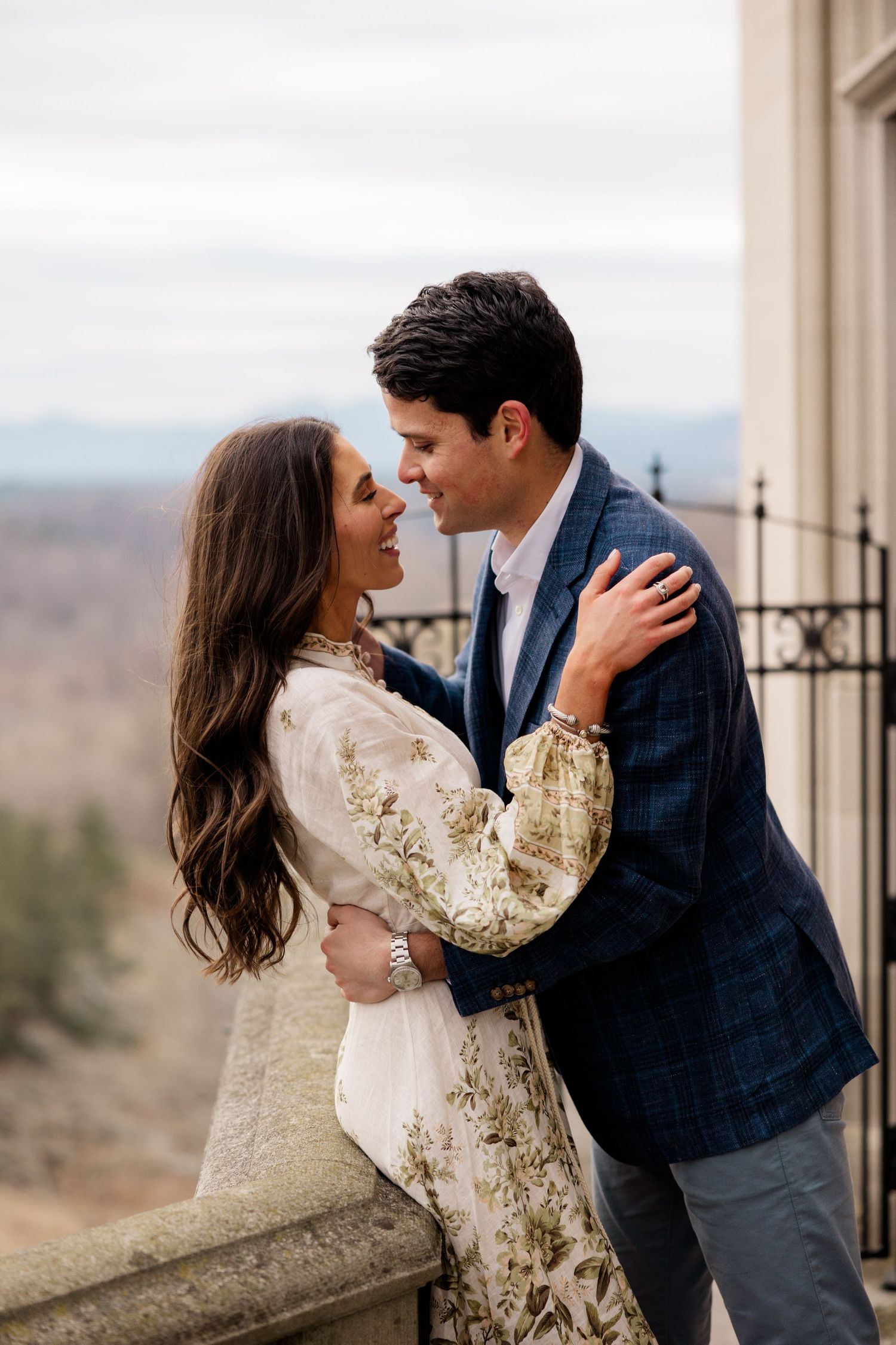 Intimate romantic moment on an elegant stone balcony overlooking distant mountain views.