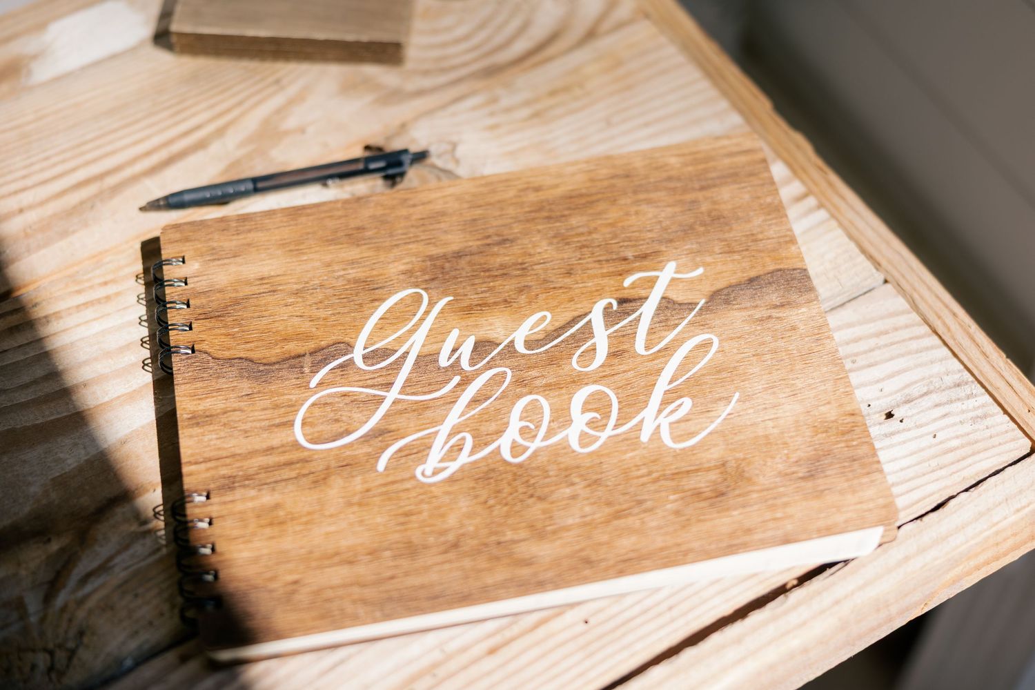 Wooden guest books with elegant calligraphy writing displayed on a rustic surface.