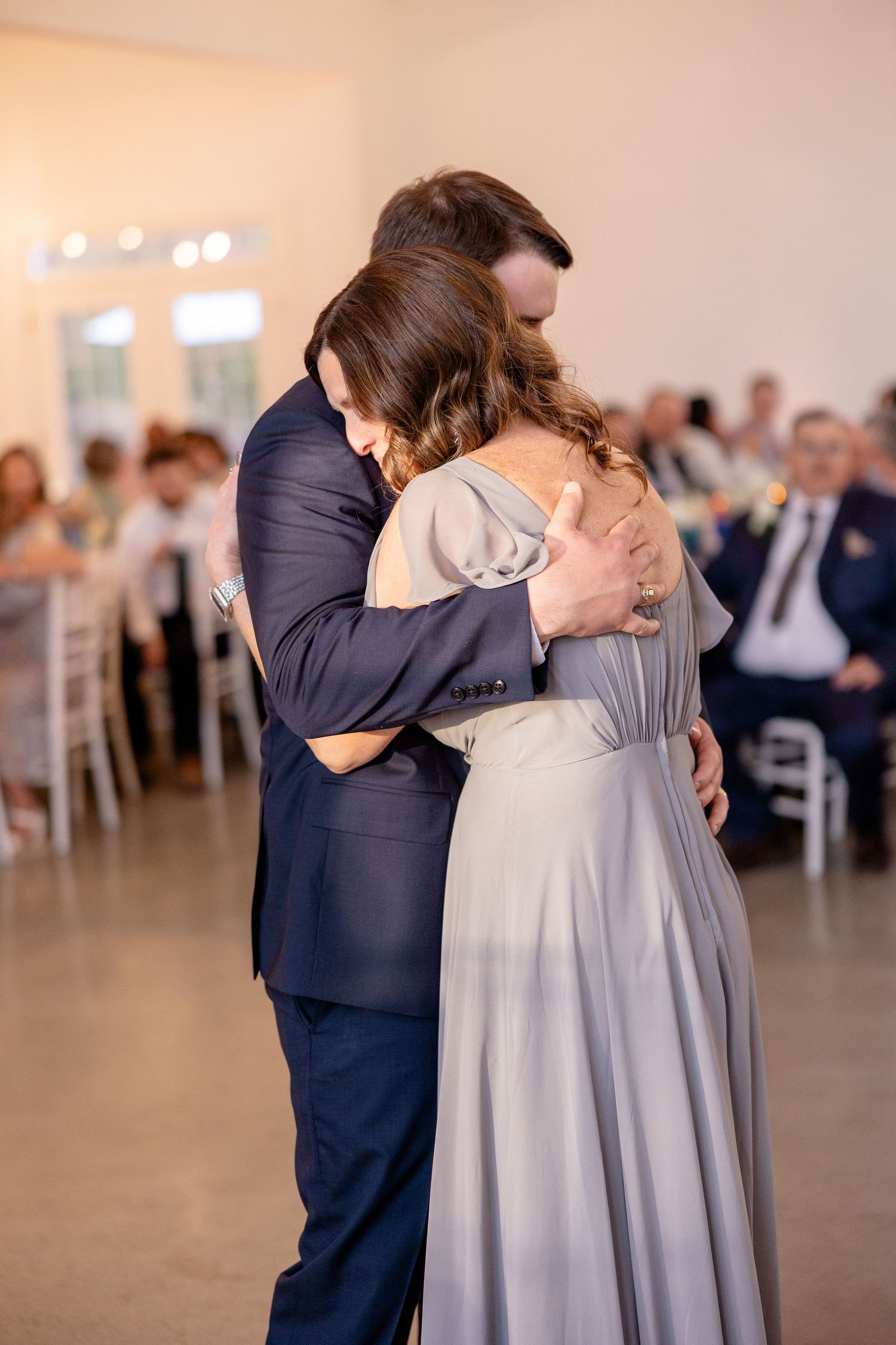 Emotional dance moment between two people in navy and gray attire.