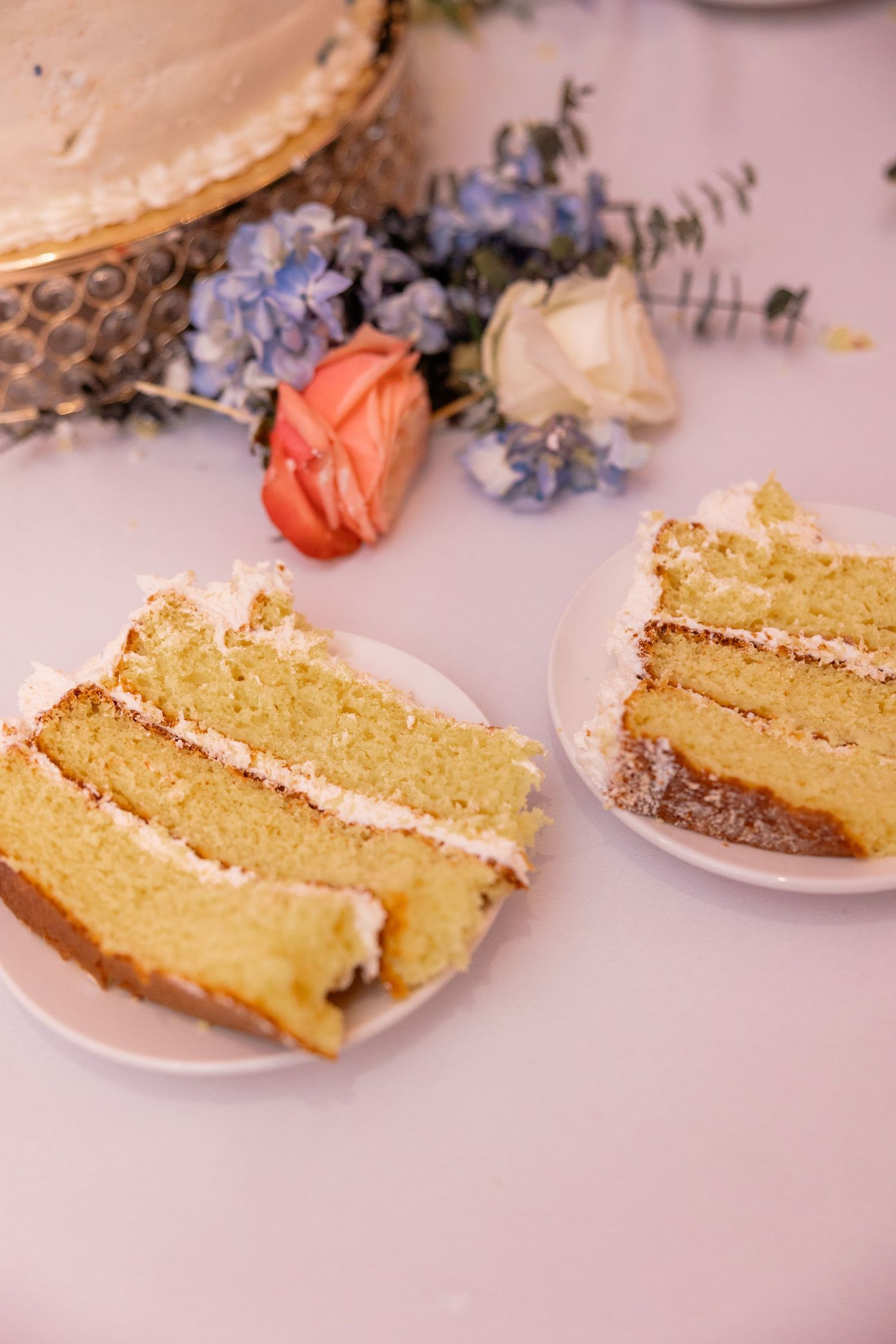 Slices of yellow wedding cake with delicate floral decorations displayed on pink plates.
