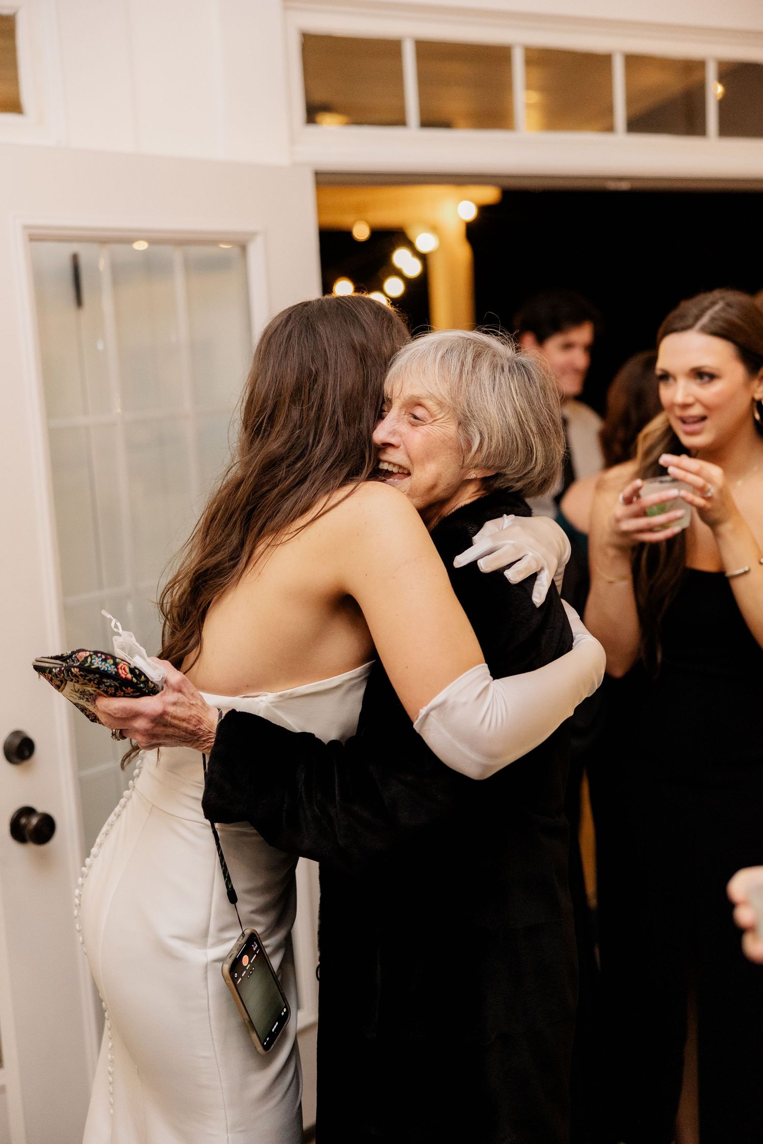 Wedding guests embrace and celebrate during reception party in indoor venue.