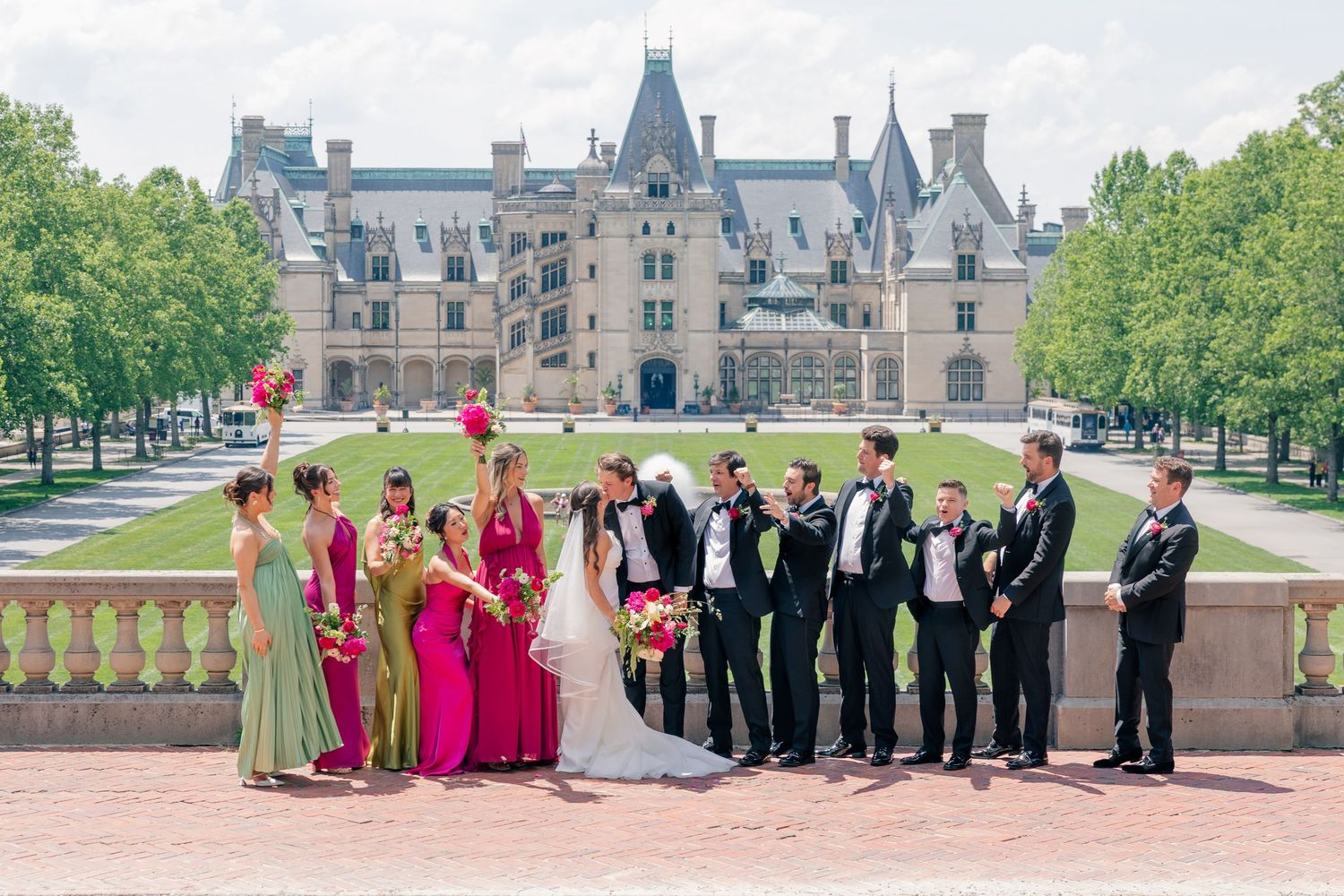 Wedding party poses in front of Biltmore Estate with bridesmaids in pink and sage green gowns.