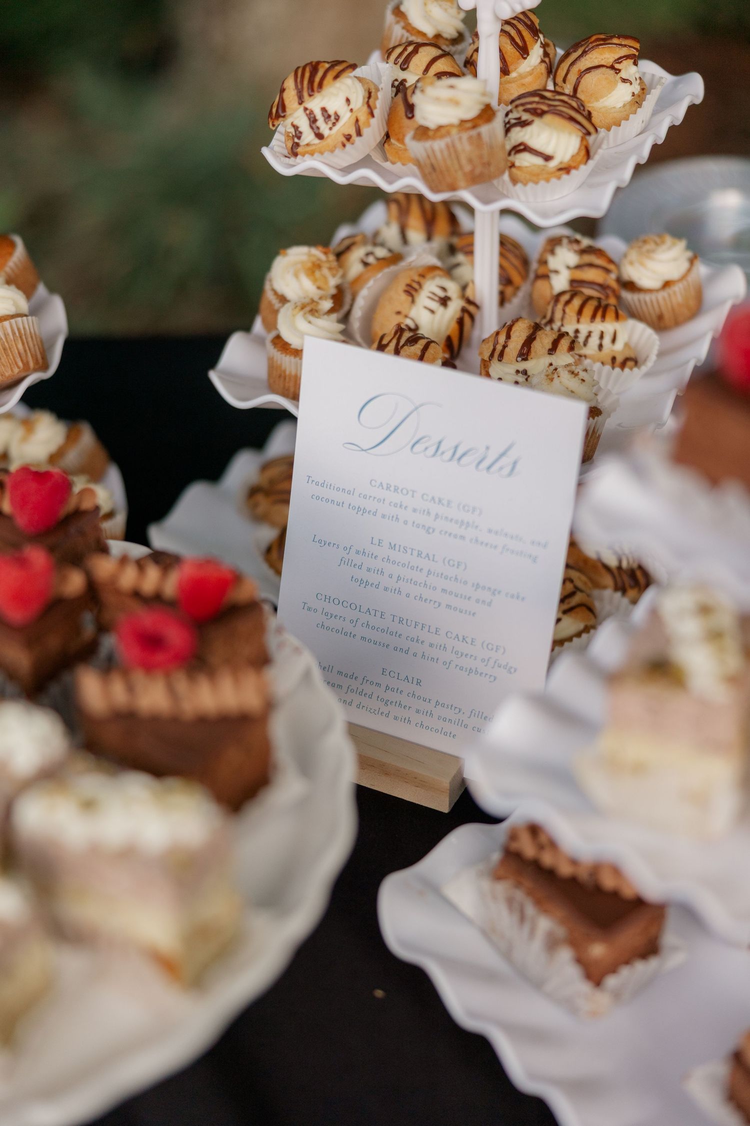 Elegant dessert display featuring pastries and treats with menu cards on tiered white serving plates.