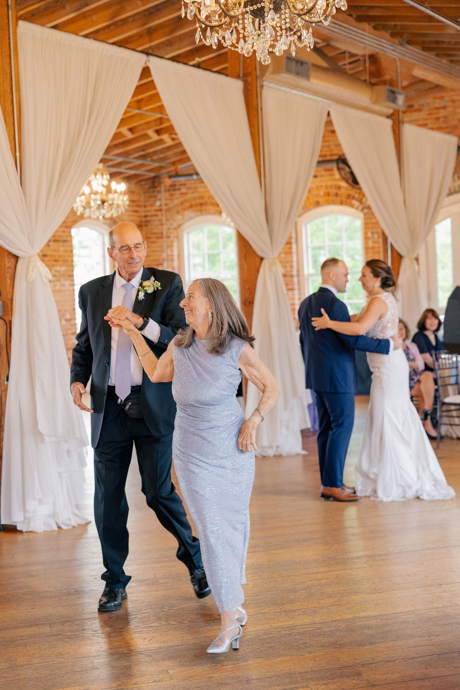 Parents join the bride and groom on the dance floor during a heartfelt wedding reception dance.